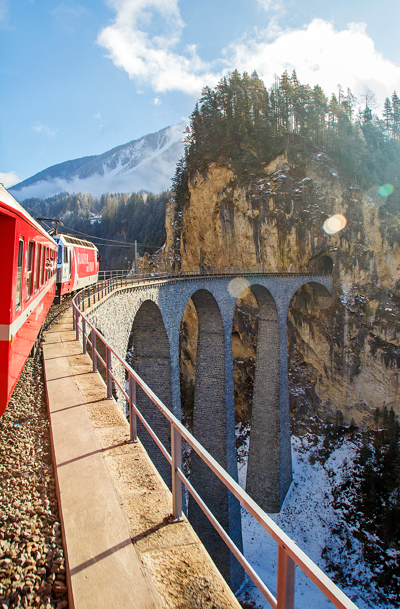 
UNESCO-Weltkulturerbe Albulabahn: Gezogen von der RhB Ge 4/4 III 651, fahren wir am 18.02.2017 mit dem RE (Chur -  St. Moritz) der Rhätischen Bahn (RhB), über den berühmten, 136 m langen und 65 m hohen, Landwasserviadukt bei Filisur, danach geht es direkt in den 216 m langen Landwassertunnel.