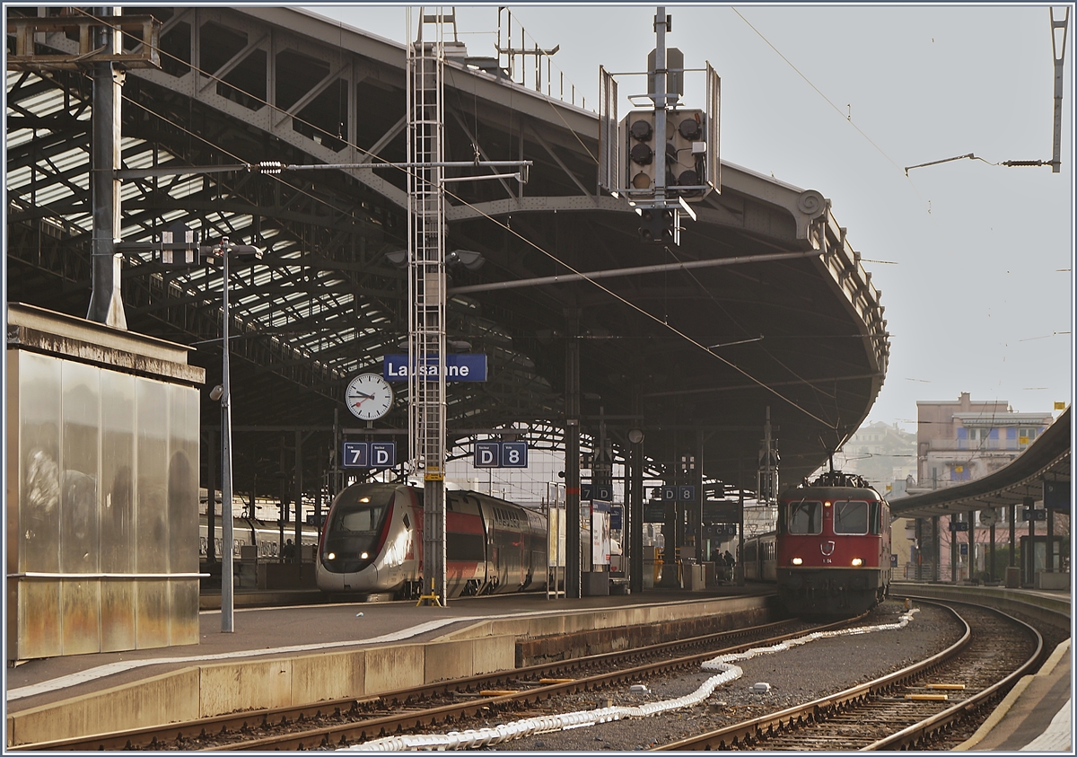 Während die SBB RE 4/4 II 11194 (und am Zugschluss die Re 4/4 II 11197) mit ihrem Dispozug einem IR 90 ersetzen wartet unter der Bahnhofshalle von Lausanne ein TGV Lyria auf die Abfahrt. 

25. Jan. 2020