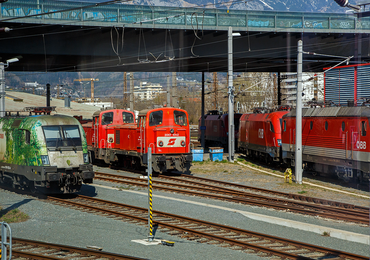 Zwei Verschubloks Methusalem der ÖBB Reihe 2067 (SGP LDH 600) abgestellt am 28.03.2022 beim Hbf Innsbruck, vorne die ÖBB 2067 101-2, dahinter eine weitere 2067 107-9, aufgenommen aus einem einfahrenden EC durch die Scheibe.

Vorne die 2067 101-2 wurde 1975 von SGP (Simmering-Graz-Pauker) im Werk Wien-Floridsdorf  (ex WLF) unter der Fabriknummer 18515 gebaut und als 2067.101 an die ÖBB (Österreichische Bundesbahnen) geliefert. 1985 erfolgte die Umzeichnung in ÖBB 2067 101-2. Die 2067 107-9 wurde 1977 von SGP (Wien) unter der Fabriknummer 18532 gebaut und als 2067.107 an die ÖBB (Österreichische Bundesbahnen) geliefert. 1985 erfolgte die Umzeichnung in ÖBB 2067 107-9.

Geschichte:
Nachdem sich Ende der 1950er Jahre die zweiachsigen Dieselloks der Reihen 2060 und 2062 für viele Aufgaben als zu schwach erwiesen, wurde von der Firma SGP (Simmering-Graz-Pauker, Werk Wien-Floridsdorf, ex WLF) die 600 PS starke, dreiachsige Baureihe 2067 (SGP LDH 600) entwickelt. Der Motor basiert auf dem Viertakt-Zwölfzylinder vom Typ SGP S12a. Die Kraftübertragung erfolgt über ein hydraulisches Voith-Getriebe (Typ L28St) auf eine Blindwelle die durch Stangenantrieb mit den drei Achsen verbunden war. Von 1959 bis 1977 wurden insgesamt 111 Lokomotiven von den ÖBB übernommen. Die Lokomotiven bis zur Ordnungsnummer 31 hatten einen kleineren Schalldämpfer (mit dementsprechend lauterem Motorengeräusch) und einen anderen Vorbau. 2001 wurde mit der Ausmusterung von Serienmaschinen begonnen, welche sich bis heute hinzieht. Vereinzelt werden sie noch für kleine Verschübe und Tunnelrettungszüge eingesetzt. 2020/2021 sind offiziell noch 10 Loks im aktiven Bestand inklusive 2067 001 und 003.

Konstruktion und Technik:
Der Lokrahmen besteht aus starken Längsblechen – diese sind mit Querträgern zu einem Kastenträger zusammengeschweißt. Auf diesem Rahmen sitzt die Antriebsanlage, die sich neben anderen wichtigen Aggregaten in dem längeren Vorbau befindet. Daran schließen das Führerhaus und ein kürzerer Vorbau an. Das Führerhaus und die beiden Vorbauten wurden in geschweißter Blechkonstruktion ausgeführt. Ab 2067 032 wurden die Klappen in Motornähe gegen Schiebetüren getauscht, was die Zugänglichkeit zum Motor erleichterte. Die Radsätze lagern bei den Loks bis 2067.81 in Gleitlagern in Ausnehmungen des Rahmens, ab 2067.82 hat man Rollenlager verwendet. Die Kraftübertragung erfolgt über die Kuppelstangen auf alle drei Achsen. Bis zur 101. Serienlok wurde das Führerstandseitenfenster als Schiebefenster ausgeführt. Die letzte Serie von 1977 von 102-111 bekamen kurbelbare Senkfenster. Viele Loks der anderen Serien wurden auf solche Fenster umgebaut. Teilweise wurde auch das fixe Fenster in der Tür gegen ein Übersetzfenster getauscht, welches die letzte Serie ebenso serienmäßig besaß.

Die Motorenkonstruktion (Typ SGP 12a) wurden von den Baureihen 2045 und 5145 übernommen. Nur wurde die Drehzahl auf 1500/min erhöht. Im Laufe der Produktion wurde eine weiterentwickelte Variante eingebaut. Die neue Bezeichnung lautete SGP S12na. Bei ein paar Loks wurde der SGP S12a gegen den SGP S12na getauscht. 13 Loks wurden in den 1990er Jahren remotorisiert und erhielten Caterpillar-Motoren. Von diesen Loks existierten 2020 noch sechs Loks.

Die Kraftübertragung vom Motor erfolgt über eine Welle auf ein hydraulisches Turbogetriebe (Zwei-Wandler-Turbogetriebe) vom Typ Voith L28/III/4-1.6 St-09, das eine Blindwelle antreibt. Die mittlere Achse ist bei der Serie 62-71 mit einem geschwächten Spurkranz, bei allen anderen seitenverschiebbar ausgeführt. Alle Loks der Baureihe 2067 verfügen über eine selbsttätige und eine nicht selbsttätige Druckluftbremse, und eine Einfache Sifa. Eine PZB ist in der Originallok nicht vorhanden, aufgrund geänderter Vorschriften wurde im TS Werk Linz 2008/2009 Versuchsweise die 2067.107 mit einer I60 nachgerüstet. Alle noch vorhandenen gewesenen Loks der jüngeren Serien und 2067.04 des Ösek bekamen ebenso eine I60. Einige bekamen auch den GSM-R-Funk.

TECHNISCHE DATEN:
Gebaute Anzahl: 112
Hersteller: SGP (Simmering-Graz-Pauker, Werk Wien-Floridsdorf, ex WLF)
Baujahre: 1959 bis1977
Spurweite:  1.435 mm (Normalspur)
Achsformel:  C
Länge über Puffer:  10.484 mm
Begrenzungslinie: UIC 505-1
Achsabstände: 4.300 mm (1.650 mm / 2.650 mm)
Raddurchmesser:  1.140 mm (neu) / 1.070 mm (abgenutzt)
Dienstgewicht: 49 t
Max. Radsatzlast : 16,2 t
Dieselmotor: 12-Zylinder-Viertakt- Dieselmotor vom Typ SGP S12na 
Nenndrehzahl des Dieselmotors: 720 – 1.500 U/min
Leistung: 442 kW (600 PS)
Anfahrzugkraft: 148 kN
Getriebe: Zwei-Wandler-Turbogetriebe vom Typ Voith L28/III/4-1.6 St-09
Zugelassene Höchstgeschwindigkeit: 65 km/h
Kleinster Krümmungsradius (v max= 10 km/h): R 80 m
Tankinhalt : 1.600 l
Bremsbauart: On-GP m Z

Quellen: ÖBB, ÖBB-Produktion GmbH und Wikipedia
