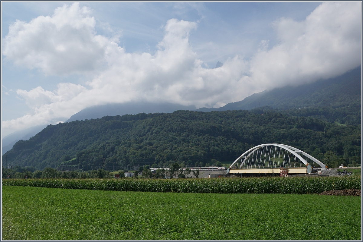 Zwischen Bex und St-Maurice überquert die Strecke Lausanne Birg die Rhone. Die alte Gittereisenbrücke wird nun durch eine sehr gefällige und unübersehbare Neukonstruktion ersetzt. Zu Zeit ist die alte Brücke schon nicht mir in Betrieb und der Verkehr verläuft einspurig über die neue Brücke, wobei vor und nach der Brücke das nördliche Gleis, dann auf der Brücke das Südliche Gleis benutzt wird, so dass die Brücke noch verschoben werden muss. Leider ist es nicht einfach, einen einigermasen guten Fotostandpunkt zu finden. Das Bild zeigt den von einer SBB Re 460 geschobenen IR 1717 von Lausanne nach Brig. 
19. August 2016