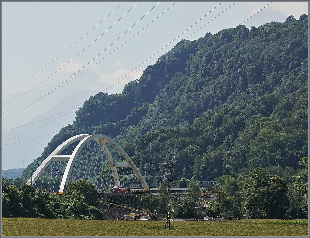 Zwischen Bex und St-Maurice überquert die Strecke Lausanne Birg die Rhone. Die alte Gittereisenbrücke wird nun durch eine sehr gefällige und unübersehbare Neukonstruktion ersetzt. Zu Zeit ist die alte Brücke schon nicht mir in Betrieb und der Verkehr verläuft einspurig über die neue Brücke, wobei vor und nach der Brücke das nördliche Gleis, dann auf der Brücke das Südliche Gleis benutzt wird, so dass die Brücke noch verschoben werden muss. Leider ist es nicht einfach, einen einigermasen guten Fotostandpunkt zu finden. Das Bild zeigt den von einer SBB Re 460 gezogenen IR 1816 von Brig nach Lausanne. 19. August 2016