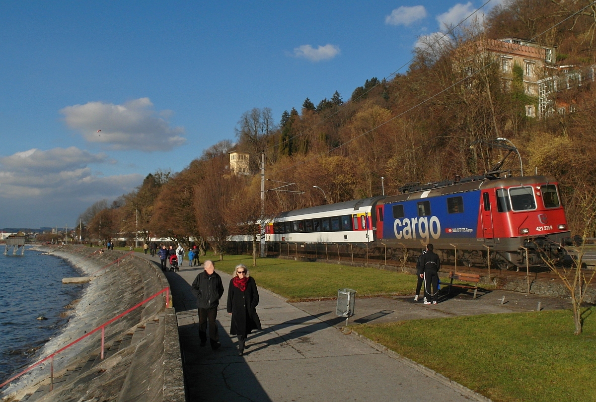 Zwischen Lochau und Bregenz führt die Bahnlinie parallel zur Uferpromenade des Bodensees entlang. Wenige Minuten nach der Übernahme der Wagen in Lindau befindet sich Re 421 379-9 mit dem EC 194, München - Zürich, hier am 25.01.2014 auf der Fahrt Richtung Zielbahnhof. Die Bregenzer sprechen bei diesem Uferabschnitt auch von der „Pipeline“, weil hier seit den 1960er-Jahren eine Ölpipeline verlief, die von Genua nach Ingolstadt führte. 1997 wurde die Pipeline stillgelegt.