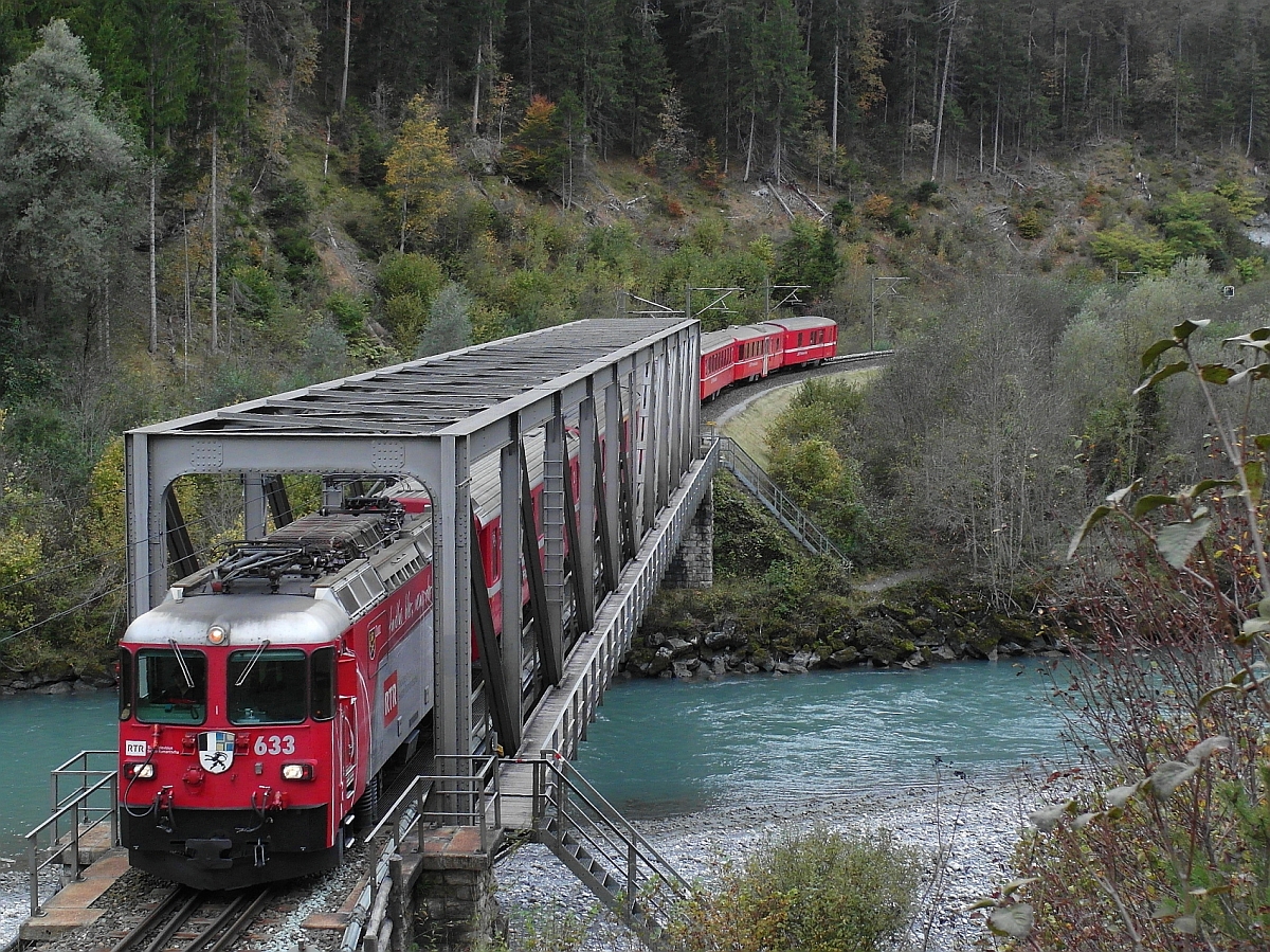 Zwischen den Stationen Versam-Safien und Trin überquert Ge 4/4 II 633 'Zuoz' mit dem RE 1257, Disentis/Mustér - Scuol-Tarasp, am 12.10.2014 den Vorderrhein.