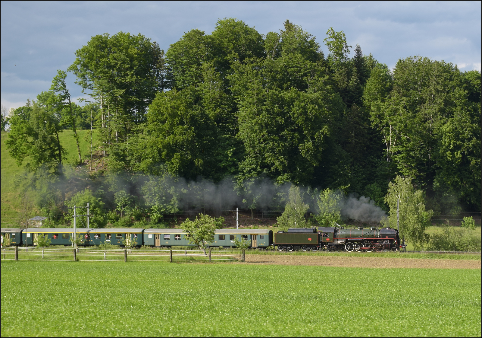 150 Jahre Emmentalbahn. 

141-R-1244 auf dem Rckweg von der grossen Emmentalrundfahrt anlsslich des Jubilums. Am Ortsausgang Menznau findet die Sonne ein Wolkenloch, freie Sicht auf die Strecke und die Strasse ist ohne Verkehr. Menznau Tuetisee, Mai 2025.