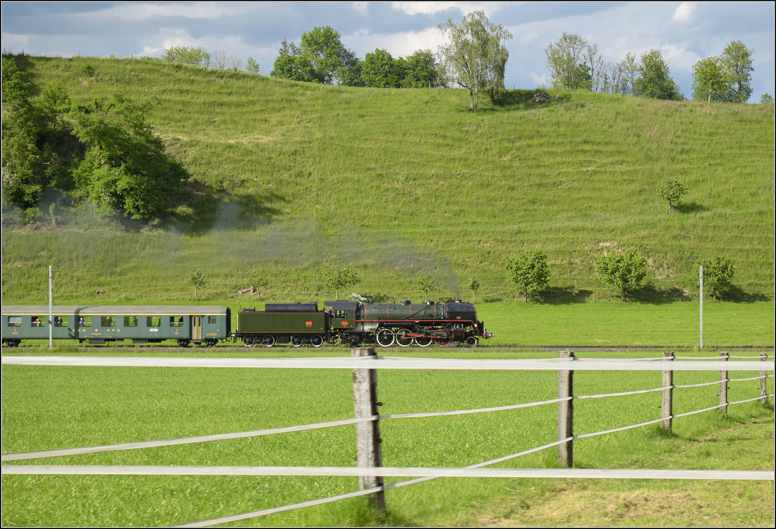 150 Jahre Emmentalbahn. 

141-R-1244 auf dem Rckweg von der grossen Emmentalrundfahrt anlsslich des Jubilums. Am Ortsausgang Menznau findet die Sonne ein Wolkenloch, freie Sicht auf die Strecke und die Strasse ist ohne Verkehr, perfekt fr eine Zugverfolgung. Menznau Neuhus, Mai 2025.