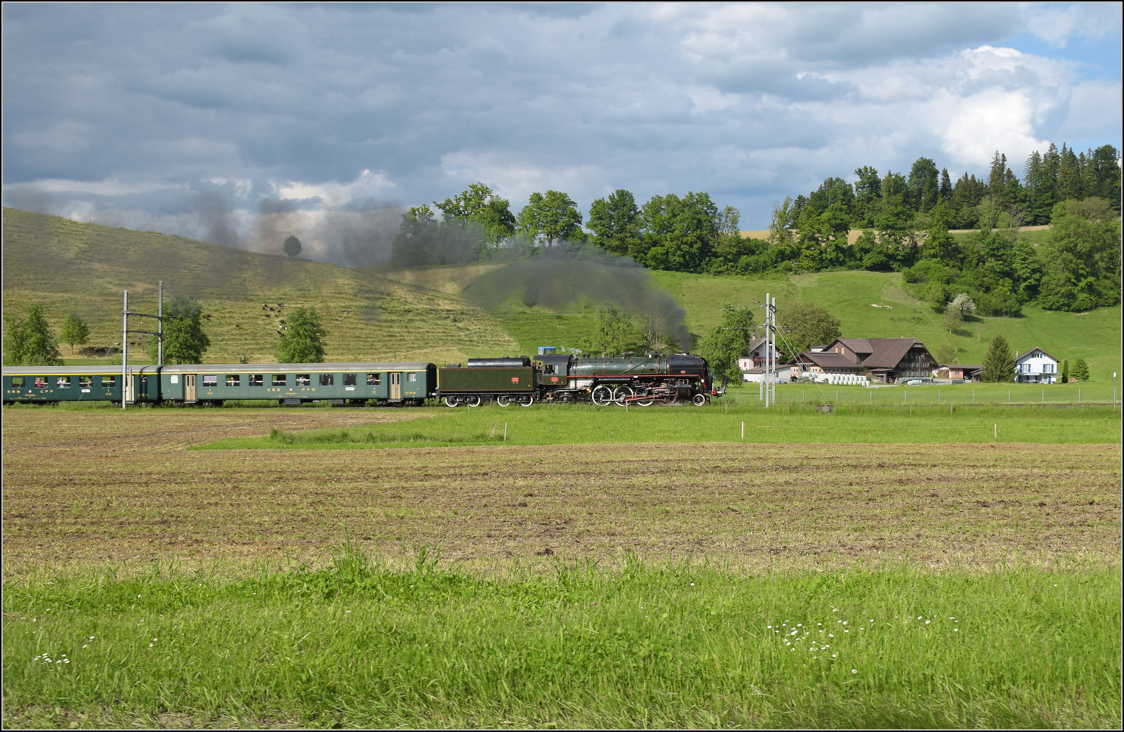 150 Jahre Emmentalbahn. 

141-R-1244 auf dem Rückweg von der grossen Emmentalrundfahrt anlässlich des Jubiläums. Am Ortsausgang Menznau findet die Sonne ein Wolkenloch, freie Sicht auf die Strecke und die Strasse ist ohne Verkehr. Menznau Hackbrett, Mai 2025.
