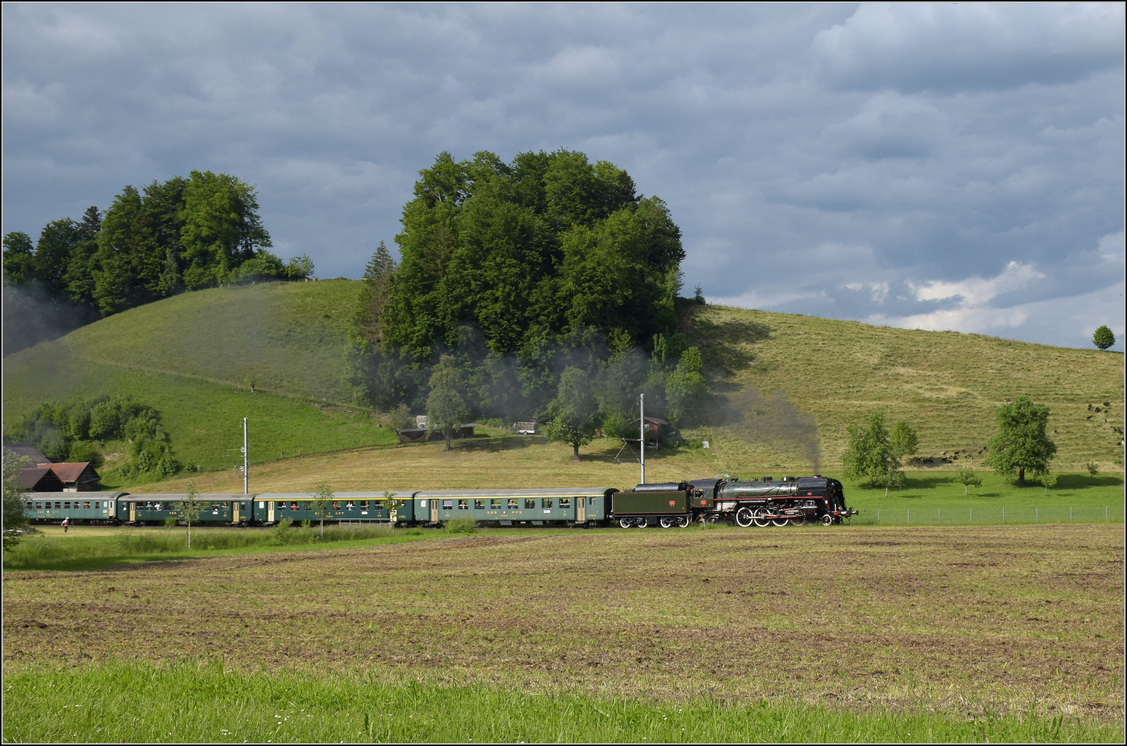 150 Jahre Emmentalbahn. 

141-R-1244 auf dem Rückweg von der grossen Emmentalrundfahrt anlässlich des Jubiläums. Am Ortsausgang Menznau findet die Sonne ein Wolkenloch, freie Sicht auf die Strecke und die Strasse ist ohne Verkehr, so begann eine kurze Parallelfahrt, wie man sie nur selten durchführen kann. Mai 2025. 