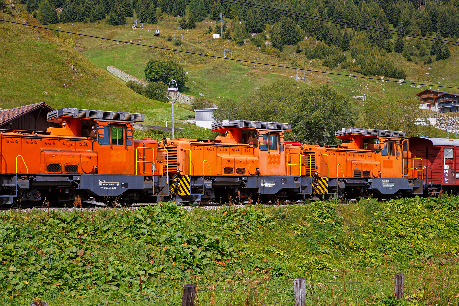 Alle drei ehemaligen dieselelektrische Rangierlokomotive der Rhätischen Bahn - RhB Gm 3/3 – 231bis 233 sind nun bei der - DFB Dampfbahn Furka-Bergstrecke AG. Hier stehen sie aufgereiht noch in der originalen RhB-Lackierung am 07 September 2021 in Realp (Uri) bei der DFB Dampfbahn Furka-Bergstrecke AG, aufgenommen aus einem fahrenden MGB-Zug heraus.

Die Gm 3/3 ist eine dreiachsige dieselelektrische Rangierlokomotive ehemals der Rhätischen Bahn (RhB). Die drei Maschinen mit den Betriebsnummern 231 bis 233 wurden zwischen 1975 und 1976 in Betrieb genommen.

Gemäß der ursprünglichen Idee sollte der Hersteller, die französische Firma Moyse /Locotracteurs Gaston Moyse), die meisten Baugruppen aus der Serienproduktion eines französischen Loktyps übernehmen. Die vielen Sonderwünsche der RhB – MTU-Dieselmotor, Vakuumbremse, Vielfachsteuerung, Führerstandseinrichtung nach RhB-Norm, erzwangen jedoch umfangreiche Änderungen und verzögerten die Lieferung der Anfang 1974 bestellten Fahrzeuge erheblich. Typenbezeichnung Moyse ist Type CF 33 EPA 500 MTL, die RhB 231 wurde 1975 unter der Fabriknummer 3553 gebaut, 1976 folgten die RhB 232 unter der Fabriknummer 3554 und die RhB 232 unter der Fabriknummer 3555.

Die Stundenleistung der maximal 55 km/h schnellen und 34 t schweren Lokomotiven beträgt 220 kW am Rad. Der Antrieb erfolgt durch einen MTU V 6-Zylinder-Dieselmotor (MTU 6 V 331 TC10) mit 386 kW (525 PS) Leistung, dieser treibt den Hauptgenerator an, welcher den elektrischen Gleichstrom-Fahrmotor elektrischen. Das Drehmoment wird vom Fahrmotor auf das nachgeschaltete Getriebe übertragen, hier kann zwischen Rangier- und Streckengang gewechselt werden. Die 3 Radsätze werden mittels Kardanwellen vom Getriebe auf die Achsgetriebe angetrieben.

Haupteinsatzgebiet dieser diesel-elektrischen Adhäsionslokomotiven bei der RhB war der Rangierdienst in Landquart, Chur und Untervaz. Dank ihrer hohen Anfahrzugkraft (im Rangiergang 153 kN) und der möglichen Doppeltraktion eigneten sich die robusten Fahrzeuge auch für den schweren Bauzugdienst. Schneeräumfahrten, gemeinsam mit der kleinen Schneeschleuder Xrotm 9216 oder der großen Xrotmt 9217, gehörten ebenfalls zum Einsatzprogramm bei der RhB. Ab Herbst 2020 wurden die drei Loks nur noch als Reserve vorgehalten, im Februar 2021 wurden sie aus dem Betrieb genommen und stillgelegt. Mitte April 2021 wurden alle drei Lokomotiven dann an die Dampfbahn Furka Bergstrecke verkauft.

Bei der DFB:
Für den schweren Rangierdienst in Realp sowie für Baulogistikfahrten im Furka-Scheiteltunnel ist die DFB auf eine leistungsfähige und zuverlässige Adhäsions-Diesellok angewiesen. Bis dahin wurde dafür die von Jung gebaute Gm 4/4 71  Elch  eingesetzt. Seit der Übernahme dieser Lok von der Matterhorn Gotthard Bahn (MGB) im Jahr 2014 hat dieses Fahrzeug den ordnungsgemäßen Unterhalt erfahren. Im Winter 2021/2022 wurde jedoch an dieser inzwischen 55-jährigen Lok eine aufwendige Totalrevision nötig.

Gleichzeitig wurde bekannt, dass die Rhätische Bahn (RhB) ihre drei Gm 3/3 231 bis 233  Moyse  durch Neufahrzeuge ersetzt, so wurde seitens der DFB Ende 2018 das Interesse an diesen Lokomotiven bekundet. Anlässlich der Verhandlungen im ersten Quartal 2021 wurden der DFB AG zwei Lokomotiven zugesagt. Als der dritten Lok die Verschrottung drohte, ergab sich für die DFB die Gelegenheit, auch diese zwecks erweiterter Ersatzteilhaltung zu übernehmen. Die Überführung (ob aus eigener Kraft ist mir unklar) der drei Gm 3/3 durch die RhB von Landquart nach Disentis/Mustér erfolgt am frühen Morgen des 12. April 2021. Am Tag darauf wurden die drei  Moyse  einzeln durch die MGB, jeweils in einen MGB-Personenzug direkt hinter einer HGe 4/4 II (gemischte  Zahnrad- und Adhäsionslokomotive) eingestellt. Die RhB Gm 3/3sind ja reine Adhäsionsloks, zwischen Disentis und Andermatt bzw. Realp gibt es ja Zahnstangeabschnitte mit bis zu 120 ‰ Neigung.

Danach ging die Dieselcrew der DFB an die Bereitstellung der ersten Gm 3/3. Am 28. Dezember 2021 konnte die Gm 231 für den Betrieb freigegeben werden. An diesem Tag und an den beiden nachfolgenden Tagen wurden theoretische und praktische Fahrzeugschulungen durchgeführt. Aktuell sind acht Lokführer auf den Gm 3/3 instruiert, weitere Schulungen werden folgen.

Danach galt es, Erfahrungen im Schneeräumeinsatz im Bahnhof Realp mit der Xrotm 9216  Schleuderina  zu sammeln. Die Gm 231 kommt außerdem für schwere Rangiermanöver zum Einsatz. Inzwischen hatten auch die Arbeiten zur Wiederinbetriebnahme der Gm 233 begonnen. Mit zwei betriebsbereiten Loks wird die Dieselcrew die Traktionsbedürfnisse auf den Adhäsionsabschnitten ohne Zahnstange flexibel abdecken können. Die Gm 232 bleibt bis auf weiteres außer Betrieb.

Status der Gm 3/3: 
Lok 231 und 233: in Betrieb
Lok 232 abgestellt (Reserve/Ersatzteilspender) 
Die UIC-Fahrzeugnummern sind 90 85 822 0231-7, 0232-5 und 0233-3.

TECHNISCHE DATEN:
Spurweite: 	1.000 mm (Meterspur)
Achsformel: C
Länge über Puffer: 7.960 mm
Achsabstände: 1.935 mm / 2.265 mm = 4.200 mm
Breite: 2.700 mm
Höhe: 3.560 mm
Dienstgewicht: 34 t
Höchstgeschwindigkeit:  55 km/h (35 km/h im Rangiergang)
Dauerleistung Dieselmotor: 386 kW (525 PS), 
Motordrehzahl: max. 2.000 U/min
Dauerleistung am Rad: 220 kW (300 PS)
Anfahrzugkraft: 153 kN (Rangiergang) / 61 kN (Streckengang)
Stundenzugkraft: 83.4 kN (Rangiergang) / 34.3 kN (Streckengang)
Treibraddurchmesser: 	920 mm (neu)
Motor: MTU V 6-Zylinder-Dieselmotor vom Typ 6V 33 1 TC10 
Antrieb: Dieselelektrisch (Drehmomentübertagung siehe Text)
Anhängelast:  35-500 t im Streckengang je nach Neigung (nur Adhäsion)
Bremssysteme: Handbremse, direkte Druckluftbremse (Rangierbremse), druckluftgesteuerte Vakuumbremse (automatische Bremse), elektrische Bremse (Widerstandsbremse)
Sicherheitssysteme: Sicherheitssteuerung (Totmann und Wachsamkeit), Zugsicherung ZSI 90, Geschwindigkeitsmesser mit Fahrtenschreiber (Farbscheibe)

Quellen: DFB Dampfbahn Furka-Bergstrecke AG, bahnonline.ch/, de.wikipedia.org/ und hellertal.startbilder.de