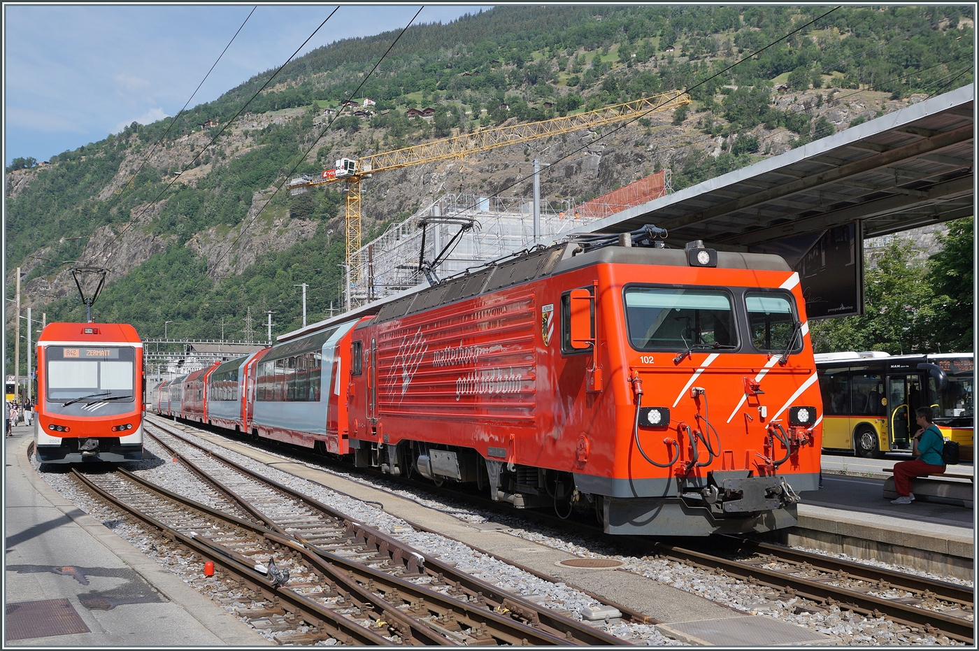 Brig (MGB) mit der HGe 4/4 II 102 mit dem Glacier Express von Zermatt nach St. Moritz und links wartet ein ABDe 4/10  Komet  auf die Abfahrt nach Zermatt. 

17. Juni 2026