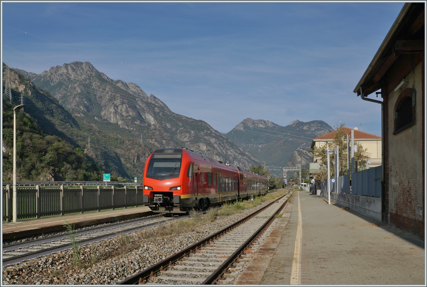 Der Blick geht vom südlichsten Bahnhof aus Richtung Norden und zeigt den als RV VdA 2718 von Aosta nach Torino Porta Nuova fahrenden FS Trenitalia BUM BTR 813 001. Er verlässt nach seinem Halt Pont S.Martin und bei der anschliessenden Weiterfahrt das Aostatal. 

12. Oktober 2023