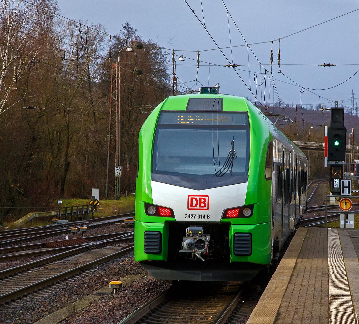 Der für die DB Regio AG – NRW fahrende dreiteilige Stadler FLIRT 3 XL 3427 014 (94 80 3427 014-0 D-STAP / 94 80 3827 014-6 D-STAP / 94 80 3427 514-9 D-STAP) der ZV VRR Eigenbetrieb Fahrzeuge und Infrastruktur, verlässt am 15.12.2022, als RE 34 „Dortmund-Siegerland-Express“ (Siegen - Letmathe - Dortmund), den Bahnhof Kreuztal.

Unter dem „grünen“ Signal (Signal Ks 1 – fahrt) wird ein „W“ als Signal Zs 2 – Richtungsanzeiger gezeigt, dies bedeutet hier das die Weiche (Fahrstraße) auf geradeaus in Richtung Welschen Ennest gestellt ist.

Der Stadler FLIRT 3 XL wurde 2020 von der Stadler Pankow GmbH in Berlin unter den Fabriknummern 42354 bis 42356 gebaut und an den Zweckverband Verkehrsverbund Rhein-Ruhr Eigenbetrieb Fahrzeuge und Infrastruktur geliefert. Eigentlich war dieser FLIRT 3 XL wie 9 weitere für die Bedienung der Regiobahnstrecke S 28 Kaarst - Neuss - Düsseldorf - Mettmann - Wuppertal vorgesehen, wo die Elektrifizierung bis 2020 erfolgen sollte. Da aufgrund von Verzögerungen der elektrische Betrieb voraussichtlich erst 2026 aufgenommen werden kann, wurden die inzwischen gelieferten Triebwagen u. a. von der DB Regio AG NRW eingesetzt.

Stadler FLIRT 3 XL, dreiteilig der BR 3427:
Die Fahrzeuge der BR 3427 vom Typ STADLER Flirt 3 XL sind, in der sogenannten XL-Ausführung, mit 67.600 mm um 4,4m länger als die normalen STADLER Flirt 3 (BR 1427), zudem haben diese 6 Türen pro Fahrzeugseite (anstatt 3). Der FLIRT verfügt über eine hohe Antriebsleistung (2.720 kW) und eine maximale Geschwindigkeit von 160 km/h. Die 3-Teiler haben 180 Sitzplätze (16 in der 1.Klasse und 154 in der 2. Klasse).

Der VRR Auftrag umfasste die Lieferung von 41 Triebzügen des Typs FLIRT. Die Bestellung teilte sich auf in 17 dreiteilige und 24 fünfteilige Fahrzeuge. Beide Fahrzeugvarianten verfügen über längere Wagenkästen, der sogenannten XL-Ausführung (FLIRT 3 XL). Ergänzend wird Stadler auch die Instandhaltung der Fahrzeuge in den kommenden 30 Jahren verantworten. Die Fahrzeuge kommen auf den Strecken des S-Bahn-Netzes Rhein-Ruhr zum Einsatz. Der FLIRT verfügt über eine hohe Antriebsleistung und eine maximale Geschwindigkeit von 160 km/h. Der helle, freundliche Fahrgastbereich ist barrierefrei und bietet dem Betreiber individuelle Gestaltungsmöglichkeiten. Sie verfügen über bequemere Sitze, überwiegend in 4er-Sitzgruppen mit Vis-à-vis-Anordnung, Toiletten sowie Steckdosen zum Aufladen von Smartphones, Tablets oder Rechnern.

Technik:
• Ausgelegt für die Verbandsfahrt von bis zu 3 Fahrzeugen
• Automatische Mittelpufferkupplungen (Scharfenbergkupplung)
• Leichtbauweise aus Aluminium
• Redundante Antriebsausrüstung bestehend aus 2 Antriebssträngen mit je einem Transformator, IGBT-Stromrichter und 2 Asynchronfahrmotoren
• Luftgefederte Fahrwerke sorgen für die erforderliche Laufruhe
• Die Fahrzeuge wurden in zwei unterschiedlichen Designs ausgeliefert (S-Bahn Rhein-Ruhr Design [grün/weß] sowie Regiobahn Design [rot/weiß])

Komfort:
• Klare Trennung von Mehrzweckbereichen für den Fahrradtransport sowie für die Beförderung von Rollstuhlfahrern
• 12 Fahrradstellplätze
• 2 extrabreite zweiflügelige Schwenkschiebetüren je Wagenkasten
• Klimatisierter Fahrgastraum und Fahrerraum
• 1 geschlossenes WC-System je EMU3 bzw. 2 geschlossene WC-Systeme je EMU5
• Einstiegshöhe 780 mm
• Modernes Fahrgastinformationssystem
• Passagier-WLAN im ganzen Fahrgastraum

TECHNISCHE DATEN (BR 3427 - Stadler FLIRT 3 XL, dreiteilig):
Spurweite: 1.435 mm (Normalspur)
Achsanordnung: Bo' 2' 2' Bo'
Länge über Kupplung: 67.600 mm
Fahrzeugbreite: 2.820 mm
Fahrzeughöhe: 4.270 mm
Fußbodenhöhe Niederflur: 780 mm
Fußbodenhöhe Hochflur: 1.150 mm
Einstiegsbreite: 1.800 mm je Tür 
Anzahl der Türen je Fahrzeugseite: 6
Sitzplätze: 180 (1. Klasse 16 / 2. Klasse 164)
Stehplätze (4 Pers./m²): 260
Dienstgewicht: 
Achsabstand im Drehgestell: 2.700 mm
Lauf- und Triebraddurchmesser: 870 mm (neu)
Höchstgeschwindigkeit: 160 km/h
Max. Leistung am Rad: 2.720 kW
Dauerleistung am Rad: 2.000 kW
Max. Anfahrbeschleunigun: 1,2 m/s²
Kupplung: Scharfenbergkupplung (Schaku) Typ 10

Quellen: Stadler Rail