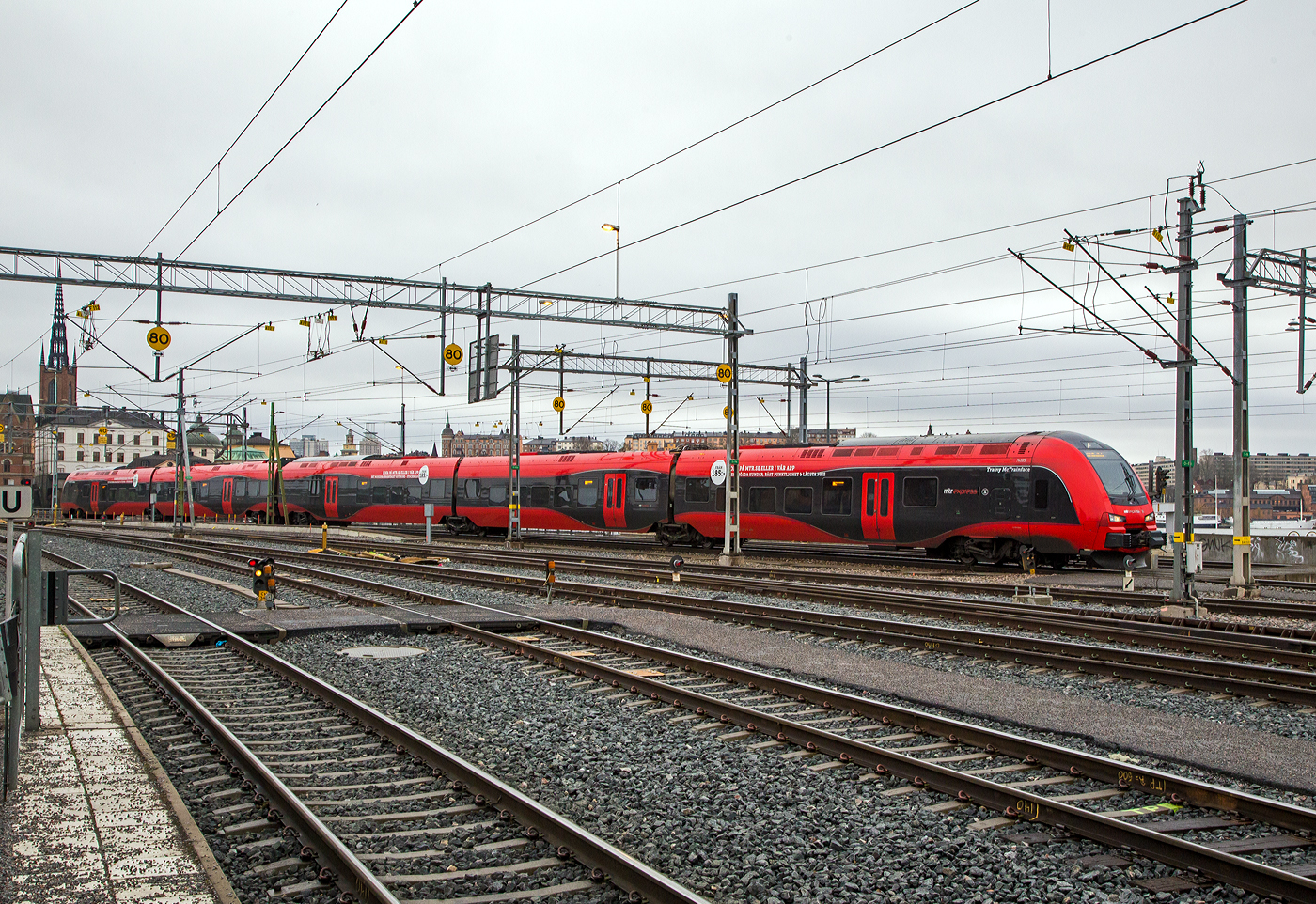 Der MTR Express X74 005, ein Stadler FLIRT 200, erreicht am 21.03.2019 Stockholm Central.

Die Baureihe MTR X74 ist ein Hochgeschwindigkeitszug, der vom Betreiber MTR Express seit März 2015 in Schweden, auf der Verbindung zwischen Stockholm und Göteborg eingesetzt wird. Die sechs beschafften Triebzüge wurden im November 2013 bei Stadler Rail in der Schweiz bestellt. Der FLIRT200 ist die Fernverkehrsausführung der FLIRT-Typenreihe. Mit der schnelleren Ausführung für den Intercity-Verkehr hat Stadler die Palette der FLIRT-Typenreihe erfolgreich erweitert.

Die Züge wurden von Stadler Rail mit einer maximalen Leistung von 4.500 kW und einer Höchstgeschwindigkeit von 200 km/h gebaut. Das Fahrzeug ist eine Version des Stadler-FLIRT-Modells, das an die norwegischen Norges Statsbaner (NSB) als NSB Type 74 und NSB Type 75 geliefert wurde. Er entspricht weitgehend den gleichen technischen Spezifikationen, jedoch mit unterschiedlicher Ausstattung. Die Züge sind so konzipiert, dass sie dem Klima in den Schweizer Alpen und im Norden standhalten.

Ein Zug besteht aus insgesamt fünf Wagen ohne Neigetechnik mit Mittelgang. Er besitzt Jakobs-Drehgestelle. Bei Bedarf können mehrere Züge gekuppelt werden.

Die Garnituren mit 2+2-Bestuhlung besitzen einen Kiosk, Steckdosen an allen Sitzplätzen, WLAN-Anschluss, behindertengerechte Einstiege und sind klimatisiert. Es gibt nur eine Wagenklasse. Der Durchgang durch den Zug ist nicht barrierefrei, da zwischen den Wagen Stufen vorhanden sind. Problematisch gestaltet sich teilweise der Weg zu den Toiletten, da von verschiedenen Sitzplätzen aus der beidseitig am Mittelgang angeordnete Kiosk durchquert werden muss. Jeder Wagen besitzt eine Doppelschiebetüre für den Fahrgastwechsel mit ausfahrbaren Trittstufen.

Innendetails sind unter anderem Wanduhren von Swiss Breitling und verstellbare Leselampen, die an den Sitzen montiert sind. Der Innenraum einschließlich der verstellbaren Sitze ist in grauer Farbe gehalten, einige Sitze haben eine rote Rückenlehne.

TECHNISCHE DATEN:
Spurweite:  1.435 mm (Normalspur)
Achsformel: Bo’2’2’Bo’+2’2’Bo’
Länge über Kupplung: 105.500 mm
Breite: 3.200 mm
Höhe: 4.380 mm
Achsabstand im Antriebsdrehgestell: 2.500 mm
Achsabstand im Laufdrehgestell: 2.750 mm
Treib- und Laufraddurchmesser: 920 mm (neu)
Dienstgewicht: 216 t
Höchstgeschwindigkeit: 200 km/h
Leistung: 4.500 kW
Anfahrzugkraft: 240 kN
Stromsystem: 15 kV 16,7 Hz ~
Sitzplätze:  244
Fußbodenhöhe: 800 mm (Niederflur) / 1.180 mm (Hochflur)

Quelle: Stadler Rail