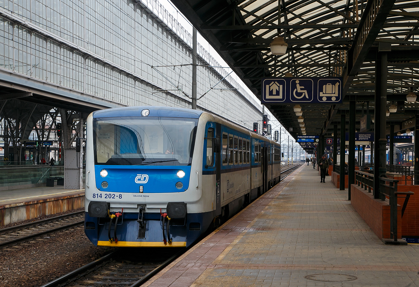 Der RegioNova „Trio“ 814 201-0 / 014 0xx / 814 202-9 steht am 23.11.2022 als Regionalzug im Hauptbahnhof Prag (Praha hlavn ndra) zur Abfahrt bereit.

Diese dreiteiligen Fahrzeuge der ČD-Baureihe 814.2/014/814.2 entstanden im Rahmen eines Rekonstruktionsprogrammes (2007 bis 2012) aus den Fahrzeugen der ČD-Baureihe 810 bzw. Beiwagen der Reihe 010. Von den ČD werden sie als „RegioNova“ vermarktet.Der Einsatz des Fahrzeuges ergibt vor allem Energieeinsparungen, eine hhere Traktionsgeschwindigkeit und dadurch eine Straffung der Fahrplne. 

Die Baureihe 814.2:
Eine Weiterentwicklung der Baureihe 814.0 ist die Baureihe 814.2. Eine Einheit besteht anstatt aus einem Motor- und einem Steuerwagen aus zwei Motorwagen (BR 814.2) und einem Mittelwagen (BR 014). Die dreiteiligen Zge bieten 127 Sitzpltze anstatt bei den zweiteiligen Wagen 76. Triebwagen der Baureihe 814.2 sind seit 2007 im Einsatz.

Technische Merkmale:
Wesentliche Vernderungen gegenber der Ursprungsbauart sind eine neue, leistungsfhigere Antriebsanlage mit dem Dieselmotor LIAZ ML 640 SE (TEDOM TD 242 RH TA25) und dem hydromechanischen Getriebe VOITH DIWA 864.3E, eine bequemere Innenausstattung mit behindertengerechter Toilette, bessere Arbeitsbedingungen fr den Lokfhrer, bessere Fahreigenschaften und geringere Umweltauswirkungen der Antriebsanlage. Die Regionova sind nach wie vor mit Schraubenkupplung ausgerstet und somit mit anderen Fahrzeugen freizgig kuppelbar.

Im Mittelwagen (BR 014), der zwischen den Radstzen einen Niederflurbereich auf etwa 50 % der Wagenlnge aufweist, befinden sich das Traglastenabteil, eine Auffahrrampe fr Rollsthle, die Toilette und 31 Sitzpltze. Der Einstieg liegt in diesem Bereich in Wagenmitte. Der Triebwagen, in normaler Bodenhhe aufgebaut, besitzt Fahrgastabteile mit 48 Sitzpltzen. Die Antriebsanlage liegt wie bei der Ursprungsbauart unter dem Wagenboden, auch die Lage der Einstiege wurde bei den Triebwagen nicht verndert.

Beschreibung von koda:
Die Zuggarnituren entstehen durch eine Rekonstruktionen und Modernisierung der ursprnglichen Wagen, die in den Jahren 1973-1983 hergestellt wurden. Der Hauptbeitrag der Rekonstruktion ist neben der Erhhung der Qualitt des Reisens auf den Regionalstrecken auch die Reduzierung der Kosten fr den Betrieb und die Wartung.

Die modernisierten Einheiten haben einen geringeren Verbrauch und in den Endstationen mssen sie nicht umgespannt werden. Der Zug Regionova  Trio  besteht aus zwei Triebwagen und einem Niederflur-Zwischenwagen, der die Befrderung von Personen mit eingeschrnkter Mobilitt und von Eltern mit Kinderwagen erleichtert.. In den Zuggarnituren ist gengend Platz auch fr greres Gepck. Eine komplette Modernisierung machte auch der Zugfhrerraum durch.

TECHNISCHE DATEN Regionova „Trio“:
Hersteller (Umbau): Pars Nova in umperk (gehrt zu koda)
Spurweite: 1.435 mm (Normalspur)
Achsformel: 1'A' + 1'1' + A'1'
Lnge ber Puffer: 42.410 mm
Wagenkastenbreite: 3.073 mm
Hhe: 3.420 mm
Leergewicht: 62,3 t
Radsatzfahrmasse: 9,75 t
Hchstgeschwindigkeit: 80 km/h
Installierte Leistung: 242 kW (bei 1.950 U/min)
Anfahrzugkraft: 54 kN
Motorentyp: 2x TEDOM TD 242 RH TA25 (LIAZ ML 640 SE)
Getriebe: 2 x Voith Diwa 864.3E
Leistungsbertragung: hydromechanisch
Sitzpltze: 127
Fubodenhhe: 570 mm (Niederflurteil)
Kleinster befahrbarer Gleisbogen: R 120 m
Bremse: DK-P
