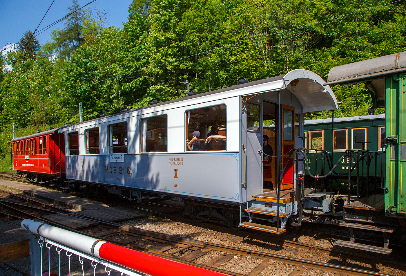 Der schmalspurige vierachsige zweite Klasse Personenwagen mit zwei Plattformen MOB B⁴ 61 seit 2016 als Geschenk von der Modellbahngruppe Obersimmental-Saanenland (MOS) bei der Museumsbahn Blonay–Chamby hier am 27 Mai 2023 im Zugverband im Museum Chaulin.

Der Wagen wurde 1906 SIG (Schweizerische Industriegesellschaft) in Neuhausen am Rheinfall als B⁴ 61 für die MOB (Montreux-Berner Oberland-Bahn) gebaut. 

Die beiden Wagen B⁴ 61 und B⁴ 62, die keine Toilette aufwiesen, wurden zusammen mit den Personenwagen BC⁴  23–26 beschafft. Grund war die Aufnahme des durchgehenden Betriebs auf der Strecke Montreux–Zweisimmen im Jahr 1905. Zudem wurden die Prognosen zur Zahl der Reisenden übertroffen. Nachdem die MOB anfänglich für die Reisezüge Drehgestell-Wagen beschafft hatte, folgten aus Kostengründen Zweiachser. Infolge von Reklamationen wechselte die MOB wiederum auf Drehgestell-Wagen, wobei es dann auch blieb.

Geschichte:
Ab 1901 in mehreren Etappen in Betrieb genommen, erreichte die Linie der Montreux-Berner Oberland (MOB) 1905 Zweisimmen. Neben der Erschließung durchquerte sie auch die bis dahin schwer zugänglichen Gebiete, insbesondere das kleine Dorf Gstaad. Das landwirtschaftliche Dorf verwandelt sich schnell in einen weltberühmten Bergkurort, es ermöglicht Touristen, die an der Waadtländer Riviera (der östlichen Teil des Nordufers des Genfersees) übernachten, direkt nach Spiez und dann nach Interlaken zu gelangen, ohne den Umweg über Bern zu machen, und gleichzeitig einen Ausflug inmitten außergewöhnlicher Panoramen zu genießen. Zudem war es damals wohl die schneller Strecke nach Spiez.

Zu diesem Zweck verband 1910 eine Expressverbindung mit Anschluss Zweisimmen Montreux in nur 4 Stunden über eine Strecke von 114 km mit Interlaken. Dieser als „Montreux-Simmenthal-Express“ bezeichnete Zug fuhr mit einem Speisewagen sowie mit Wagen der 1. Wagenklasse, was damals auf einer Nebenbahn sehr selten war. Insgesamt war das Rollmaterial von Anfang an mit einem hohen Maß an Komfort ausgestattet, wie der „B 61“, mit 30 Sitzplätzen (Polstersessel) in der 2. Klasse. Wie damals üblich war in allen Zügen auch eine dritte Klasse mit Holzbänken vorhanden; 1956 wurde das System auf europäischer Ebene mit 2 Klassen vereinheitlicht. Die bequemen historischen Polstersessel wurden dann 1956 durch Holzbänke ersetzt, dadurch hatte der Wagen nun 40 Sitzplätzen in der „neuen“ 2. Klasse. Der „B 61“ beendete seine „aktive“ Karriere bei der MOB Ende der 1979 im Regionalverkehr, insbesondere zwischen Montreux und Les Avants. Er wurde 1979 für 100 Franken an die MOS - Modellbahngruppe Obersimmental-Saanenland (MOS) verkauft. Die MOS nutzte ihn von 1979 bis 2015 als Vereinslokal in Saanen, zusammen mit dem 1995 übernommenen ursprünglichen MOB BFZe 4/4 26 und K 529. 2015 musste die Modellbahngruppe (heute aufgelöst) den Standort in Saanen infolge Sanierung der Bahnstrecke und des Bahnhofes aufgeben und verlegte diesen nach Zweisimmen. Sie schenkte in der Folge 2016 den Wagen B⁴ 61 (ohne Inneneinrichtung) der Museumsbahn Blonay–Chamby. Bei der BC wurde er komplett überholt und in den Originalzustand, einschließlich der bequemen historischen Polstersessel, versetzt. Am 10. Mai 2018, anlässlich des „Mega Steam Festival“ dem 50-jährigenJubiläums der BC wurde er in Dienst gestellt und präsentiert. 
TECHNISCHE DATEN:
Hersteller: SIG (1906) 
Spurweite: 1.000 mm (Meterspur)
Achsanzahl: 4 (in 2 Drehgestellen)
Länge über Puffer: 11.630 mm 
Länge Wagenkaten: 10.630
Höhe / Breite: 3.600 mm / 2.700 mm
Drehzapfenabstand: 6.500 mm 
Achsabstand im Drehgestellt: 1.200 mm
Drehgestelle Typ: SIG, einfache Federung
Laufraddurchmesser: 750 mm (neu)
Eigengewicht: 9.800 kg
Sitzplätze: 30 (40 mit Holzbänken von 1956 bis 1979)
Höchstgeschwindigkeit: 50 km/h
Kupplungen: Mittelpuffer mit einer Schraubenkupplungen (Zp 1)

Quellen: Museumsbahn BC, x-rail.ch und wikipedia
