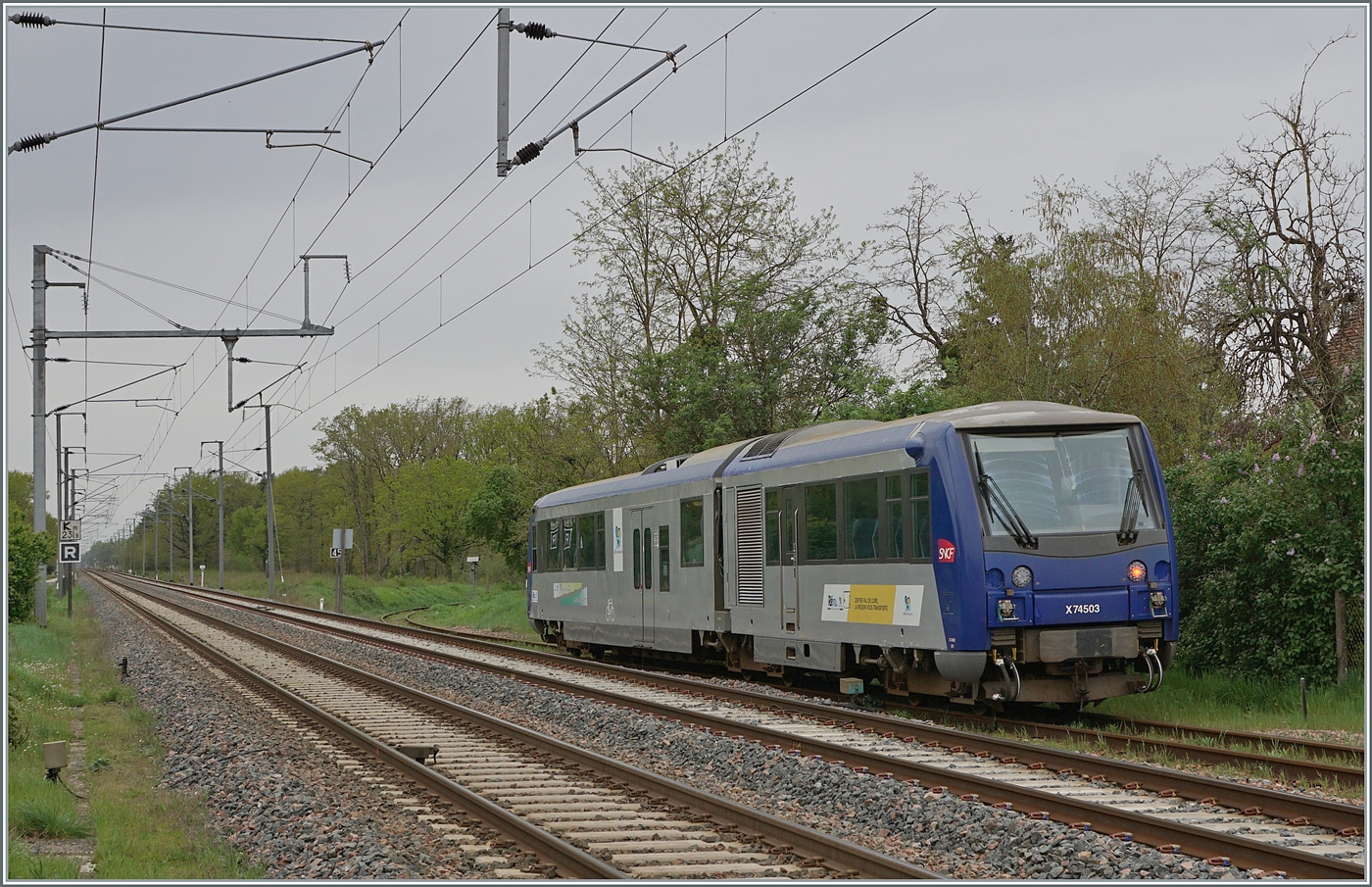 Der SNCF Schmalspur Dieseltriebwagen X 74503 ist als TER 61285 von Salbris nach Valençay unterwegs und verlässt nach einem recht langen Halt von neun Minuten den Bahnhof von Gièvres. In Gièvres besteht Anschluss an die Normalspurstrecke Tours - Vierzon, deren Gleise im Vordergrund im linken Bildteil zu erkennen sind. Leider fuhren jedoch zur Verkehrszeit des TER 61285 keine Normalspurzüge.  

Die lange Aufenthaltsdauer ergab für mich kein Sinn, aber eine gute Gelegenheit, den Zug dabei etwas ausgiebiger zu fotografieren. Der relativ lange Aufenthalt des TER 61285 den  ich bereits bei der Planung für diesen Fotoausflug festgestellt hatte, war auch der Grund gerade diesen Zug in Gièvres zu fotografieren.  

7. April 2024