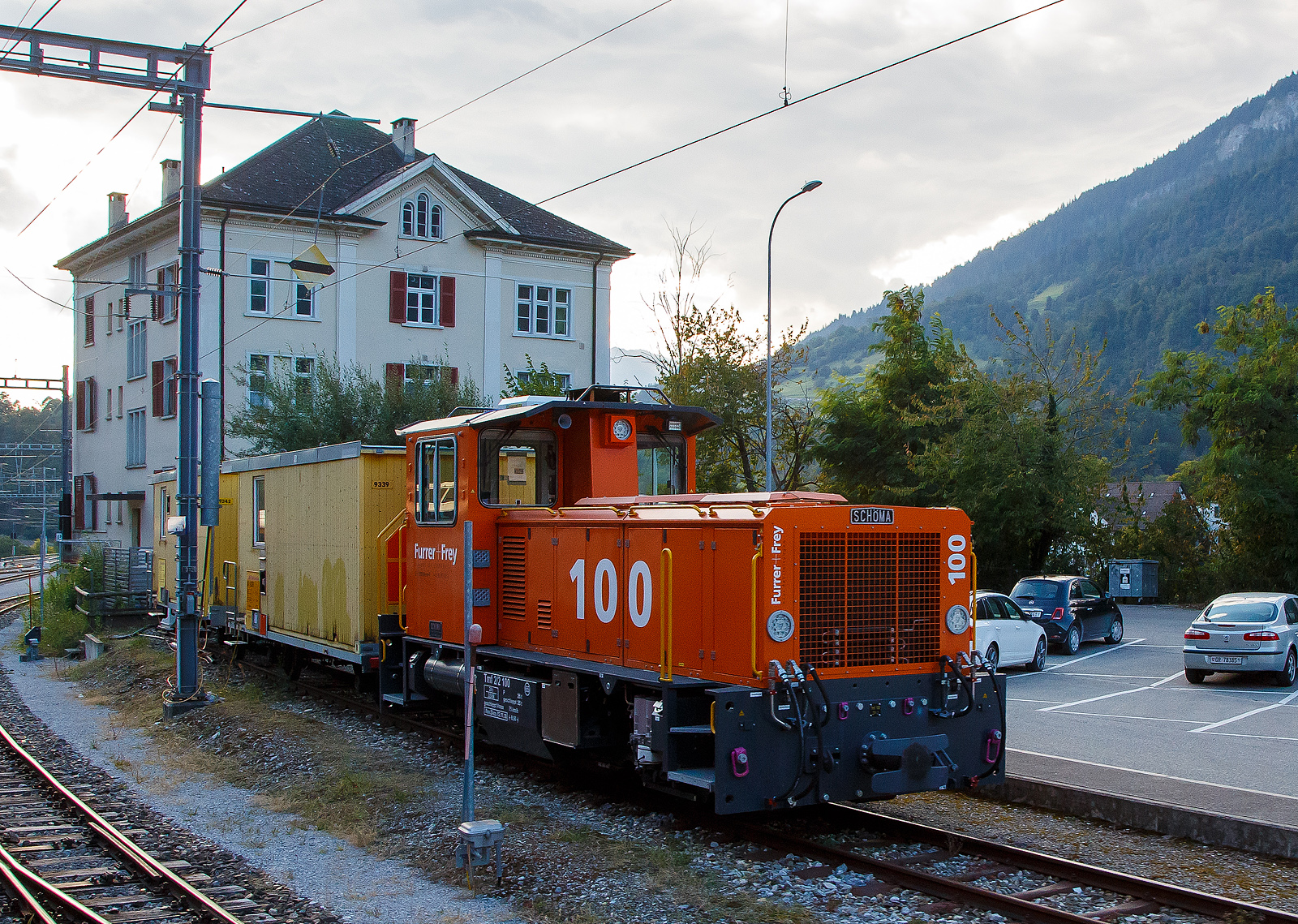 Der Tmf 2/2 100 der Furrer+Frey AG steht am 06.09.2021 beim Bahnhof Reichenau-Tamins (aufgenommen aus dem Zug heraus).

Das Meterspur-Multitalent der Furrer+Frey AG (Bern)...
Kupplungen, Bremssysteme und Zug- und Stossvorrichtungen des neuen Tmf 2/2 mit Funkfernsteuerung erlauben seinen Einsatz auf allen Schweizer Meterspurbahnen.

VIELSEITIG:
Der Schma Tmf 2/2 (100) ist fr den Einsatz auf Steigungen bis 70 Promille geeignet.
Er ist ausgerstet mit Magnetschienenbremse, Vakuumbremse und sowohl 4 bar als auch 5 bar Druckluftbremsen.
Dank verstellbaren Zug- und Stossvorrichtungen und dem Radprofil C kann er auer beim Tram auf allen Schweizer Meterspurbahnen eingesetzt werden.
Auf den Einbau einer Zugsicherung wurde fr dieses Baustellenfahrzeug verzichtet. Die Systeme der Bahnen sind so verschieden, dass sie sich teilweise gegenseitig ausschlieen.

Die Meterspur-Lok vom Typ SCHMA CFL 250 BCL-R wurde 2018 von SCHMA (Christoph Schttler Maschinenfabrik GmbH) in Diepholz unter der Fabriknummer 7007 gebaut, am 07.11.2018 erfolgte die Auslieferung an die Furrer + Frey AG, Bern [CH]  als Tmf 100. Auch wenn sie nur als Tmf 100 gefhrt wird hat sie die UIC-Nummer 99 85 8290 100-9 CH-FFAG.

TECHNISCHE DATEN:
Baujahr: 2018
Spurweite: 1.000 mm (Meterspur)
Achsfolge: B
Lnge ber Puffer (abh. V. installierten Kupplungstyp): GFN - 8.870 mm / ZP1 - 8.470 mm / ZP2 - 8.340 mm
Achsabstand: 3.750 mm
Triebraddurchmesser 850 mm.
Achsabstand 3.750 mm.
Breite 2.670 mm
Hhe 3.650 mm
Breite: 2 700 mm
Eigengewicht:  28,0 t
Hchstgeschwindigkeit: 65 km/h (75 km/h Schleppfahrt)
Dieselmotor: Wassergekhlter Caterpillar  6-Zylinder-Reihen-Viertakt-Dieselmotor mit Turboaufladung vom Typ CAT C13 ACERT
Motorleistung: 354 kW (481PS)
Motor Hubraum: 12,5 l (Bohrung 130 mm x Hub 157 mm)
Retarder:  Voith VR 120-3 
Lastschaltgetriebe: DANA 8422H-257, 4 Gnge fr jede Fahrtrichtung
Bedienung: aus Fhrerstand und/oder Funkfernsteuerung
Steigung / Geflle: Zugelassen fr den Betrieb bis 70 ‰
Bremse: Druckluftbremse (4 oder 5 bar) und Vakuumbremse
Anhngelasten: berfhrungsbetrieb Bau- und Manverbetrieb
bis 10 ‰ 130 t bei 40 km/h max. 350 t bei 15 km/h
bis 15 ‰ 95 t bei 40 km/h max. 325 t bei 10 km/h
bis 20 ‰ 70 t bei 40 km/h max. 250 t bei 10 km/h
bis 30 ‰ 40 t bei 40 km/h max. 170 t bei 10 km/h
bis 40 ‰ 35 t bei 40 km/h max. 125 t bei 10 km/h
bis 50 ‰ 22 t bei 30 km/h max. 95 t bei 10 km/h
bis 60 ‰ 18 t bei 30 km/h max. 75 t bei 10 km/h
bis 70 ‰ 10 t bei 30 km/h max. 60 t bei 10 km/h

Bemerkungen: Das Fahrzeug ist mit einem Partikelfilter ausgerstet.
Transport auf LKW-Tiefgnger, Eigenfahrt oder Verlad auf Bahnwagen.
Auf- und Ablad mit Kran, Anschlagmittel teils vorhanden. 
Ausgerstet mit Radprofil C, welches Einstze auf allen Meterspurbahnen in der Schweiz erlaubt.
Es knnen alle in der Schweiz vorkommenden Typen von Zug- und Stovorrichtungen, mit unterschiedlichen Hhen, montiert werden (GFN, ZP1 und ZP2).
Zulassung: Schweiz: Meterspur (ohne Meterspur Tram)

Quelle: Furrer + Frey AG
