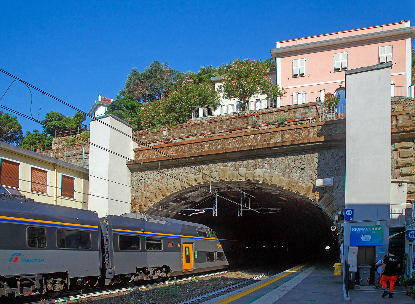 Der Trenitalia “Rock” ETR 521-048, ein fünfteiliger Elektrotriebzug vom Typ Hitachi Caravaggio, hat am 22.07.2022 den Bahnhof Riomaggiore (Cinque Terre) erreicht. Er fährt als Cinque Terre Express (Regionale) von La Spezia Levanto, via Riomaggiore, Manarola, Corniglia, Vernazza, Monterosso, nach Levanto. Der Bahnhof von Riomaggiore liegt am nordwestlichen Ortsrand, nur drei bis vier Wagenlängen befinden sich unter freiem Himmel, der Rest in den beiden Tunneln (davor und dahinter).