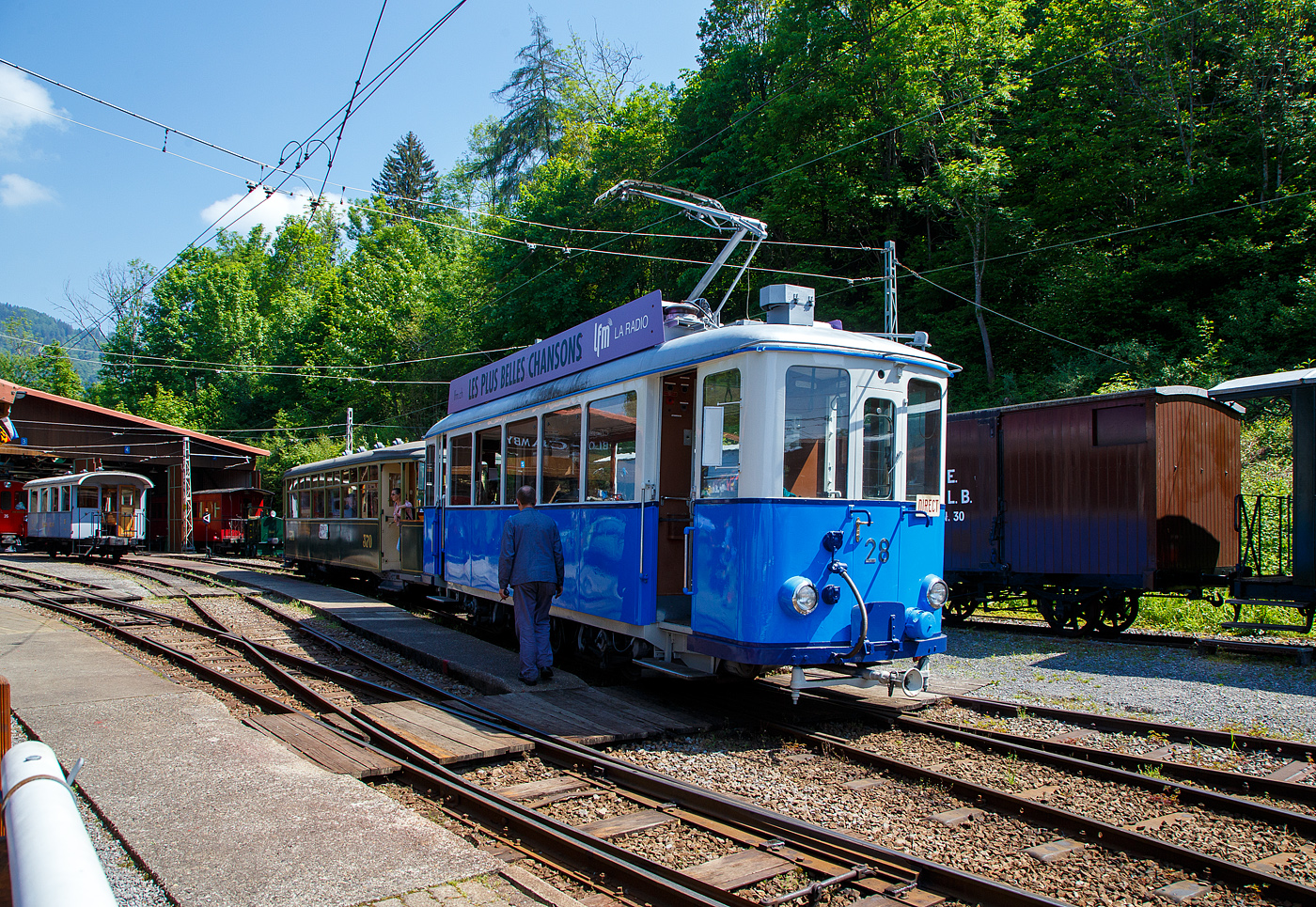 Der Triebwagen Ce 2/3 28 der Museumsbahn Blonay–Chamby, ehemals der TL - Transports publics de la région lausannoise (deutsch Öffentliche Transporte der Region Lausanne), ex Genève Veyrier 23, rangiert am 27.05.2023  im Museums-Areal der Museumsbahn Blonay–Chamby in Chaulin.

Der Triebwagen Ce 2/3 wurde ursprünglich 1913 als Zweiachser für die Genève Veyrier als Nr. 23 von SWS und SAAS gebaut. Bereits 1919 ging er an die TL. Die Werkstätte der TL baute ihn1948 um, die Aufbauten wurden modernisiert und der Wagen bekam eine zusätzliche Mittelachse um die Antriebsachsen beim Durchfahren von Kurven zu führen. Der Verschleiß wurde somit stark reduziert und der Komfort stark verbessert. 1963 wurde die Jorat-Linie stillgelegt und der Triebwagen, sowie ein weiterer, gingen an die BVB. Der ex TL Ce 2/3 – 28 wurde 1976 an die Blonay-Chamby verkauft und ist eines der letzten Überbleibsel der Lausanner Straßenbahnen.

TECHNISCHE DATEN des Ce 2/3 – 28
Spurweite: 1.000 mm
Achsformel: A 1 A
Länge über Puffer: 11.030 mm
Achsabstand: 2 x 2.100 mm (4.200 mm)
Breite: 2.150 mm
Höhe: 3.350 mm
Dienstgewicht: 15.8 t
Treibraddurchmesser: 880 mm (das Laufrad ist wesentlich kleiner)
Höchstgeschwindigkeit.: 55 km/h
Leistung: 2 x 88 kW = 176 kW
Getriebeübersetzung: 1:5,93
Spannung: 900 V DC
Sitzplätze: 24 (3. Klasse)
Stehplätze: 46
