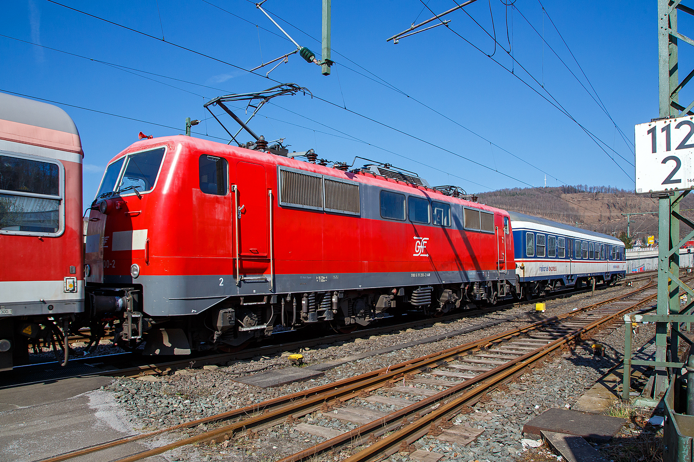 Die 111 200-2 (91 80 6111 200-2 D-GfF) der Gesellschaft für Fahrzeugtechnik mbH, eingereiht in einen National Express Personenzug am 24.03.2021 bei einer Zugdurchfahrt durch Niederschelden, hier passiert er gerade den Bü 343 (Km 112,183 der Siegstrecke KBS 460).

Die Lok wurde1982 von Krupp unter der Fabriknummer 5511gebaut, der elektrische Teil wurde von AEG unter der Fabriknummer 9026 geliefert. Bis 2019 war die Lok bei der DB Regio.
