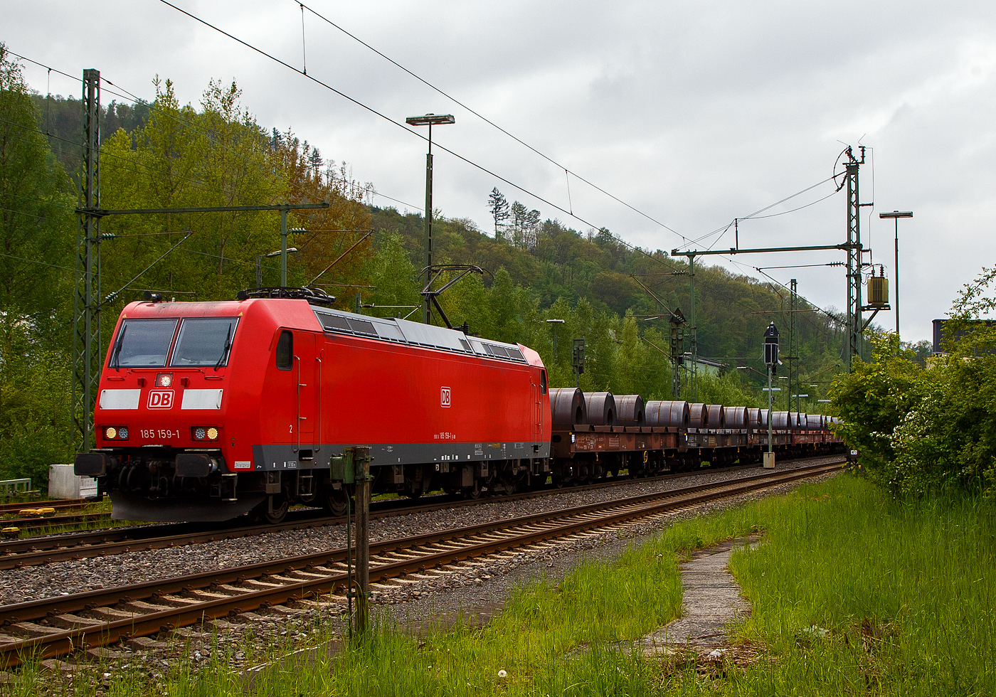Die 185 159-1 (91 80 6185 159-1 D-DB) der DB Cargo AG fährt am 11.05.2023, mit einem Warmband-Coilzug (offene sechsachsige Wagen der Gattung Sahmms etc.), durch Niederschelden in Richtung Siegen bzw. Kreuztal.

Die TRAXX F 140 AC1wurde 2003 von der Bombardier Transportation GmbH in Kassel unter der Fabriknummer 33632 gebaut.
