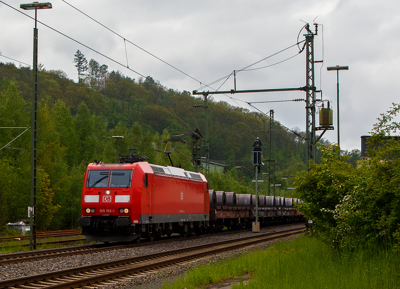 Die 185 159-1 (91 80 6185 159-1 D-DB) der DB Cargo AG fährt am 11.05.2023, mit einem Warmband-Coilzug (offene sechsachsige Wagen der Gattung Sahmms etc.), durch Niederschelden in Richtung Siegen bzw. Kreuztal.

Die TRAXX F 140 AC1 wurde 2003 von der Bombardier Transportation GmbH in Kassel unter der Fabriknummer 33632 gebaut.