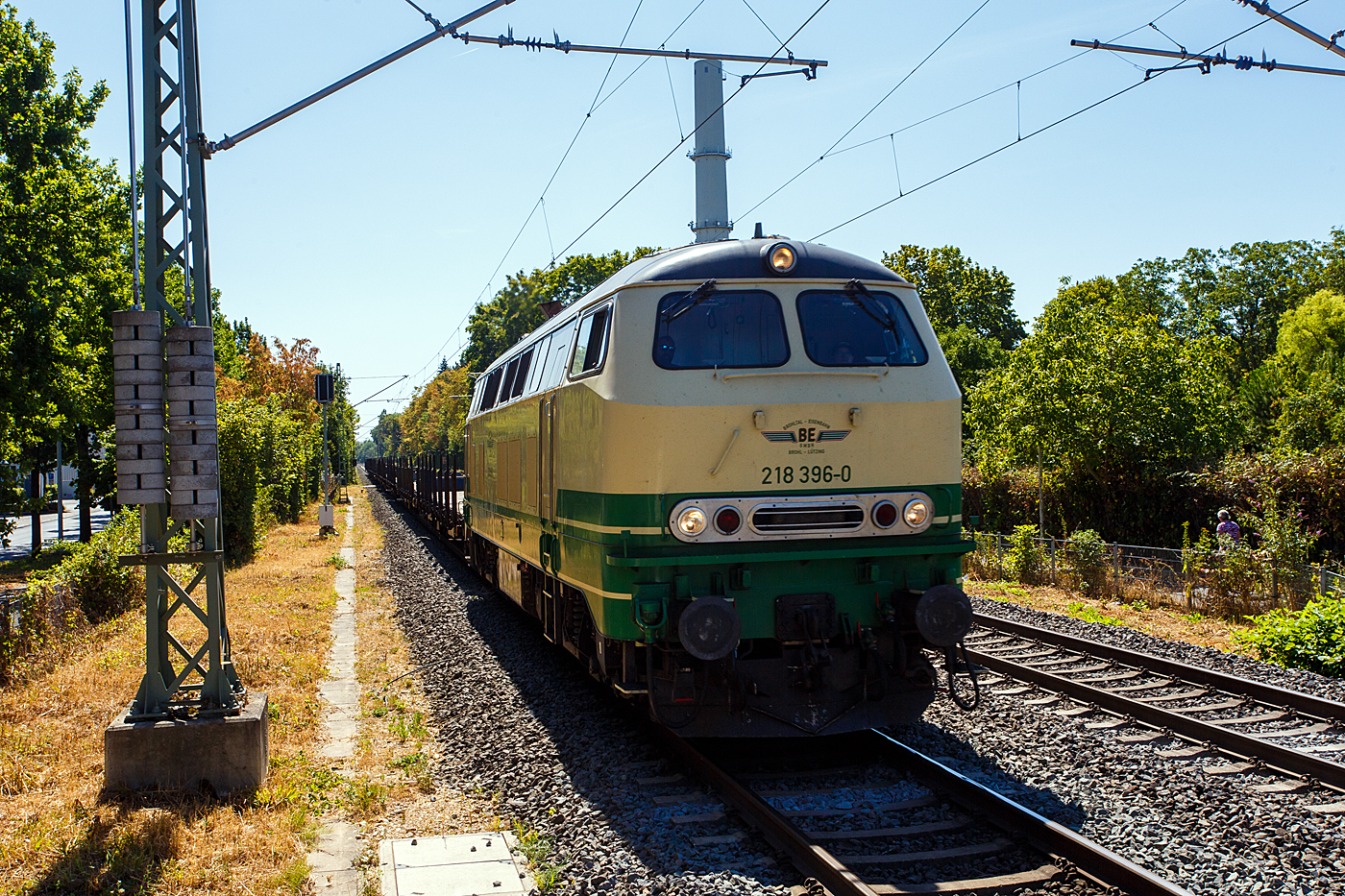 Die 218 396-0 (92 80 1218 396-0 D-BEG) der BEG - Brohltal-Schmalspureisenbahn Betriebsgesellschaft mbH (Brohl-L�tzing) f�hrt am 12 August 2026, mit einem Flachwagenzug, durch den Bahnhof Bonn UN Campus in Richtung K�ln.

Die V164 wurde 1975 bei MaK in Kiel unter der Fabriknummer 2000118 gebaut und als 218 396-0 an die Deutsche Bundesbahn geliefert. Am 01.04.2017 erfolgte die Ausmusterung bei der DB Regio AG und die Lok wurde an die BEG verkauft.

Die Lok hat einen wassergek�hlten V12-Zylinder- Viertakt-Dieselmotor mit Direkteinspritzung, Abgasturboaufladung und Ladeluftk�hlung vom Typ MA 12 V956 TB10 (Grundlage von MAN) mit einer Leistung von 1.839 kW (2.500 PS).

TECHNISCHE DATEN:
Spurweite: 1.435 mm (Normalspur)
Achsformel:  B'B'
Spurweite:  1.435 mm
L�nge: 16.400 mm
Drehzapfenabstand:  8.600 mm
Achsabstand im Drehgestell: 2.800 mm
Gewicht: 79 Tonnen
Achslast: 20 t
H�chstgeschwindigkeit: 140 km/h
Motor: Wassergek�hlter V 12 Zylinder Viertakt MTU - Dieselmotor vom Typ 12 V 952 TB 10 mit Direkteinspritzung, Abgasturboaufladung und Ladeluftk�hlung
Motorleistung: 1.839 kW (2.500 PS) bei 1.500 U/min
Motorhubraum: 114.7 Liter
Motorgewicht (trocken): 9.950 kg
Getriebe: MTU-Getriebe K 252 SUBB (mit 2 hydraulische Drehmomentwandler)
Leistungs�bertragung: hydraulisch
Tankinhalt:  3.150 l
Bremse: KE-GPP-R-H mZ
