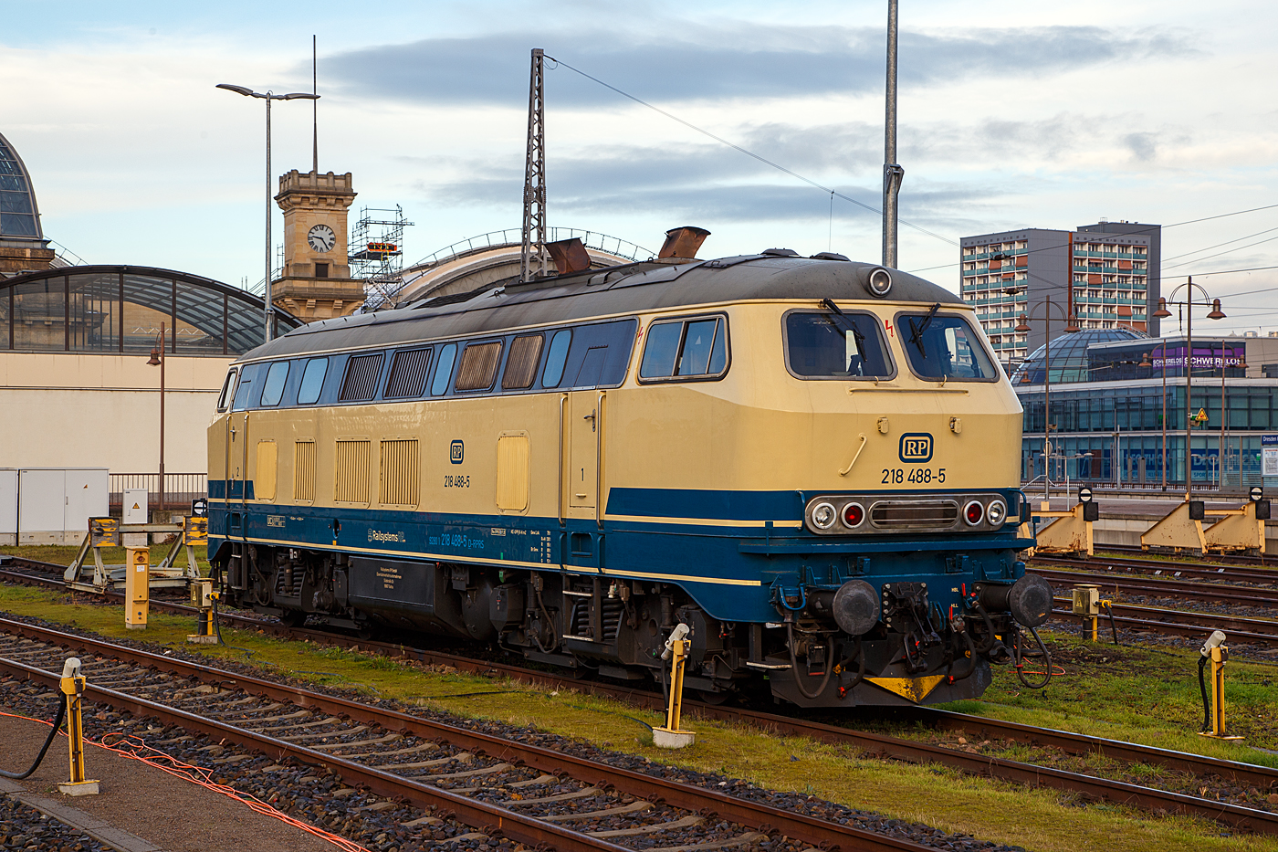 Die 218 488-5 (92 80 1218 488-5 D-RPRS) der Railsystems RP GmbH (Gotha) ist am 08.12.2022 auf einem der Abstellgleisen im Hauptbahnhof Dresden (Ost) angestellt.

Die V 164 wurde 1978 von der Krauss-Maffei AG in München-Allach unter der Fabriknummer 19803 gebaut und an die DB geliefert, bis 2018 war sie in verkehrsrot im Bestand der DB Regio Südost (Leipzig). Nun ist sie bei der Railsystems RP GmbH. Die Lok hat die Zulassungen für D, A, B, CH, F, DK und CS (Serbien und Montenegro).

Die Railsystems RP GmbH halt als Einsatzbestand 11 Fahrzeuge dieser Baureihe. Die 218 488 hat eine 36-polige Doppeltraktions- und Wendezugsteuerung, sowie eine Zugsammelschiene (AEG). 

TECHNISCHE DATEN:
Spurweite: 1.435 mm (Normalspur)
Achsformel:  B'B'
Spurweite:  1.435 mm
Länge: 16.400 mm
Drehzapfenabstand:  8.600 mm
Achsabstand im Drehgestell: 2.800 mm
Gewicht:  79 Tonnen
Achslast: 20 t
Höchstgeschwindigkeit:  140 km/h
Motor: Wassergekühlter V 12 Zylinder Viertakt MTU - Dieselmotor vom Typ 12 V 952 TB 10 mit Direkteinspritzung und Abgasturboaufladung mit Ladeluftkühlung
Motorleistung: 1.839 kW (2.500 PS) bei 1.500 U/min
Anfahrzugkraft: 235kN / Dauerzugkraft: 175kN
Getriebe: MTU-Getriebe K 252 SUBB (mit 2 hydraulische Drehmomentwandler)
Leistungsübertragung: hydraulisch
Tankinhalt:  3.150 l
Bremse: KE-GPP-R-H mZ
Besonderheiten: doppeltraktionsfähig / wendezugfähig, elektrische Zugsammelschiene
