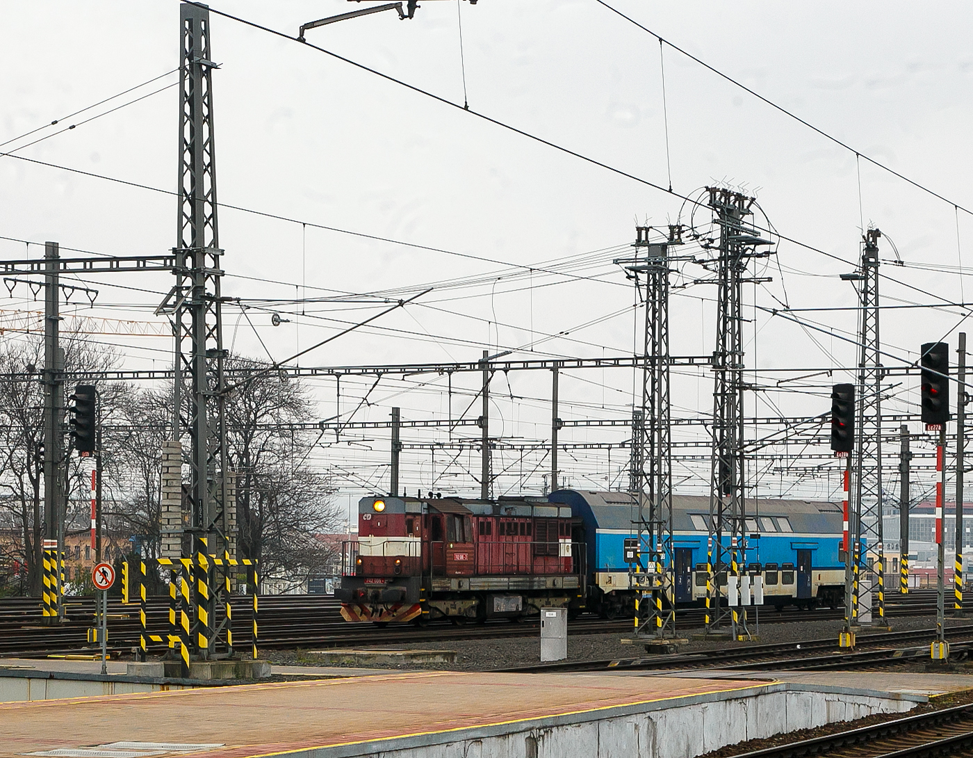 Die ČD 742 086-2 (CZ- ČD 92 54 2 742 086-2) fhrt am 23.11.2022, mit dem  2. Klasse klimatisierten Doppelstock-Reisezugwagen, CD-CZ 50 54 26-18 141-6, der Gattung Bdmteeo 296 (ex CD-CZ 50 54 26-18 141-6, Bmto 292), in den Prager Hauptbahnhof (Praha hlavn ndra) ein. Der 44 t schwere Wagen verfgt ber 126 Sitzpltze, 8 Stellpltze fr Fahrrder und ein geschlossenes WC-System.

Die Diesellok  Kocour   oder  Tranzisto   (Kater, Transistor):
Die ČSD-Baureihe T 466.2, ab 1988 Baureihe 742 sind dieselelektrische Gterzug- und Rangierlokomotiven der ehemaligen Tschechoslowakischen Staatsbahn (ČSD). Die Entwicklung begann 1970 mit den beiden Prototypen der BR T 475.15 (744.5). 

Das Leistungswachstum in der Motortraktion sowie die Notwendigkeit von Fortschritten bei der Erneuerung der Dampftraktion und der knftigen Typenvereinheitlichung des Motorlokparks veranlassten das Verkehrsministerium, die Beauftragung der Entwicklung und anschlieenden Produktion einer neuen Lokomotive zu prfen. Diese sollte fr mittelschweren bis schweren Rangierdienst, leichteren Gleisdienst, aber auch im Gter- und Personenverkehr, bestimmt sein.

Zwei Prototyp-Lokomotiven der Reihe T 475.15 (744.5) wurden 1970 von ČKD in Praha gebaut, wurden aber von der ČSD als ungengend abgelehnt. Dies lag hauptschlich an ihrem Fhrerstand,  whrend die ČSD einen Turmfhrerstand mit guter Sicht verlangte, hatten diese Lokomotiven einen Fhrerstand neben dem hinteren Ende der Lokomotive, sodass die Aussicht nicht sehr zufriedenstellend war. Die Maschinen der Baureihe T 475.15 wurden daher verworfen und stattdessen die neuen Lokomotiven der Baureihe T 466.0 (735) produziert. Die Produktion erfolgte ab 1972 im Turčiansk strojrny in Martin. 1973 begann bei ČKD Prag die Produktion neuer Lokomotiven der Reihe T 448.05 (740.5), die fr den Bedarf groer Industrieunternehmen und fr den Export bestimmt waren. Die Produktion von Lokomotiven T 466.0 (735) bei TS Martin verzgerte sich noch, die Entwicklung von Lokomotiven der Baureihe T 466.1 blieb erfolglos, auerdem war geplant, die Produktion von Lokomotiven bei TS Martin einzustellen und das Werk auf die Waffenproduktion zu konzentrieren . Auch die bereits produzierten T 466.0 (735) Maschinen waren im Betrieb sehr unzuverlssig. Die Situation in der Flotte der ČSD-Motorlokomotiven ist daher unertrglich geworden. Deshalb hat sich die ČSD eine Notlsung einfallen lassen: 1976 bestellten sie bei der ČKD 60 neue Lokomotiven der Baureihe T 466.2 (742), die genau aus den Industriemaschinen der T 448.05 (740.5) entstehen sollten. Die Serie, die bereits seit drei Jahren in der Industrie im Einsatz war, mit zudem sehr guten Ergebnissen. Die Liste der erforderlichen Umbauten war recht lang: Gewichtsreduzierung, Umbau des Triebwerks, Einbau einer Zugsicherung, Umbauten im elektrischen Teil, Umbau der Bremsen.1977-78 wurden 60 Lokomotiven der 1. Serie gebaut geliefert und die neuen Maschinen wurden fast sofort auf CSD in Betrieb genommen. Die 2. Serie folgte sofort und eine weitere danach. Die Produktion der Lokomotiven T 466.2 (742) fr die ČSD endete mit der 9. Serien im Jahr 1986; insgesamt erwarb ČSD 453 dieser Lokomotiven. Whrend der langjhrigen Produktion gab es mehrere partielle 

Modifikationen an der Konstruktion der Maschine – ab der 2. Serie mehrgliedrige Lenkung und Zugkraftwhler, ab der 3. Serie eine Knickbrcke seitlich am krzeren Vorbau, ab der 6. Serie wurden Jalousien auf dem Dach der Lokomotive installiert und ab der 7. Serie neue Fahrmotoren. 41 Lokomotiven wurden fr den Bedarf der Industrie geliefert, Maschinen auf Basis der Baureihe T 466.0 ČSD wurden auch nach Vietnam und Bangladesch geliefert. Nach der Produktion von Lokomotiven T 466.2 (742) fr ČSD erfolgte 1987-88 die Produktion von abgeleiteten Lokomotiven T 466.3 (743) fr Adhsionsbetrieb auf Steilstrecken.

TECHNISCHE DATEN der BR 742, ex T 466.2:
Hersteller: ČKD Praha
Baujahre: 1977 bis 1986
Hergestellt e Anzahl: 453 fr die ČSD (in 9 Serien), 41 weiter fr andere
Spurweite: 1.435 mm (Normalspur)
Achsfolge: Bo'Bo'
Lnge ber Puffer: 13.580 mm ( am 4. Serie13.600 mm)
Hhe: 4.472 mm
Breite: 3 130 mm
Drehzapfenabstand: 6.700 mm
Achsabstand im Drehgestell: 2.400 mm
Treibrad-: 1.000 mm (neu) / 920 mm (abgenutzt) 
Dieselmotor: 6-Zylinder-Viertakt-Reihen- Dieselmotor mit Direkt-Einspritzung und Turbolader vom Typ ČKD  K 6 S 230 DR
Motorhubraum: 64,75 Liter (Zylinder- 230 mm / Kolbenhub 260 mm)
Kompressionsverhltnis: 12,5 : 1
Nenndrehzahl: 1.250 U/min (Leerlaufdrehzahl 510 U/min)
Motorgewicht (ohne Generator): 7.700 kg
Achsbersetzung: 1:4,8125
Dauermotorleistung: 883 kW (1.200 PS)
Leistung des Traktionsgenerators: 780 kVA
Leistungsbertragung: dieselelektrisch
Fahrmotorentyp: TE 005 E / ab 7. Serie TE 015 C
Antriebsmotorleistung: 195 kVA
Hchstgeschwindigkeit: 90 km/h
Dienstgewicht: 64 t
Anfahrzugkraft: 192kN
Dauerzugkraft: 121 kN
Max. Tankinhalt: 4.000 l
Kleinster bef. Halbmesser: R 80 m

Quellen: Wikipedia, atlaslokomotiv.net
