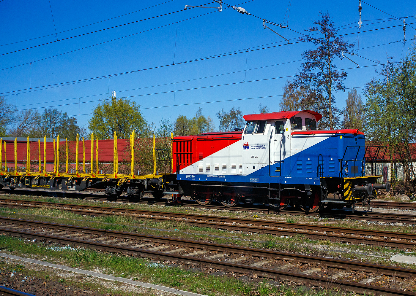 Die 345 414-7 (98 80 3345 414-7 D-RFH) der Rostocker Fracht- und Fischereihafen GmbH, ex RFH 1, ex Minol 3, übernimmt am 22 April 2026 bei Rostock Holbeinplatz einen leeren Rungenwagen-Zug (TWA Wagen der Gattung Snps mit Rungensystem ExTe). Aufnahme aus einer S-Bahn heraus. 

Die V 60 ost (bzw. V 60 D oder V 60.12) wurde 1982 bei LEW (VEB Lokomotivbau Elektrotechnische Werke „Hans Beimler“, Hennigsdorf) unter der Fabriknummer 17692 gebaut und im November 1982 in die damalige Minol - VEB Kombinat Mineralöl und Oleum Berlin für das Tanklager Rostock als Lok 3 geliefert. Bei der ab 1990 als Minol Mineralölhandel AG firmierenden war die V 60 bis 1995 und ging dann im April an die RFH - Rostocker Fracht- und Fischereihafen GmbH, wo sie erst als Lok 1 bezeichnet wurde. 

Die vierachsigen dieselhydraulischen Rangierlokomotiven V 60 D für den mittelschweren Rangierdienst waren neben dem Einsatz bei der Deutschen Reichsbahn auch bei diversen Werk- und Grubenbahnen zu finden. Etwa 25 Prozent der Lokomotiven wurden exportiert, in RGW-Staaten und in das Nichtsozialistische Wirtschaftsgebiet. So erhielten unter anderem die Ägyptischen Staatsbahnen, die BDŽ und die SNTF diese Lokomotiven. Die Entwicklung stammt aber nicht LEW in Hennigsdorf, sondern sie wurden ab 1955 vom VEB Lokomotivbau Karl Marx Babelsberg (LKM) entwickelt die auch die ersten 188 Stück als V 60.10 bis 1964 baute.
