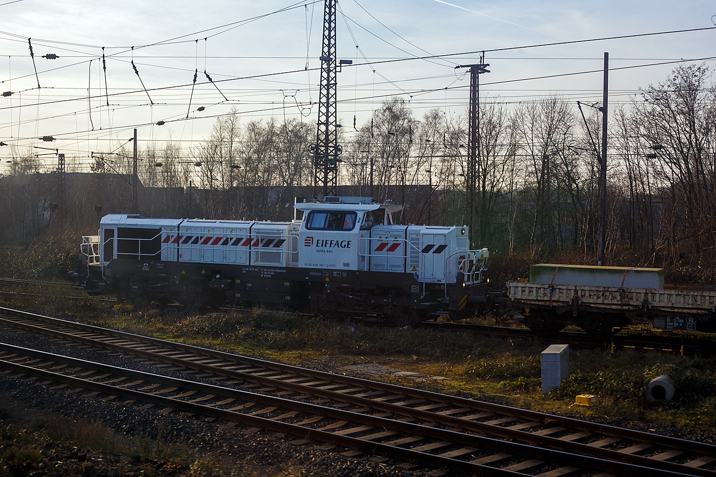 Die 4185 142-1 (92 80 4185 142-1 D-ERD) eine dieselelektrische Vossloh DE 18 der Eiffage Infra-Rail GmbH schient einen Bauzug am 21 Januar 2025 in den Abstellbereich (Schieneninfrastruktur) der Eiffage Infra-Rail GmbH in Herne (ehemals Heitkamp Rail GmbH). Bild aus einem IC heraus.

Die DE 18 wurde 2023 von der Vossloh Rolling Stock GmbH (teil der chinesischen CRRC-Gruppe) in Kiel unter der Fabriknummer 5502565 gebaut und im November 2023 an die Eiffage Infra-Rail GmbH in Herne geliefert, die in Deutschland 4 dieser DE 18 besitzt. 

Eiffage ist ein börsennotiertes französisches Bauunternehmen mit Firmensitz in Vélizy-Villacoublay. In Deutschland hat die Eiffage Infra-Rail GmbH ihren Sitz in Herne. Im Jahre 2010 übernahm Eiffage von Heijmans den Bereich Schieneninfrastruktur der ehemaligen Firma Heitkamp. Die Gleisbaugeräte und die zugehörige Werkstatt sind auf dem Gelände der ehemaligen Heitkamp Bauholding in Herne-Wanne beheimatet.

