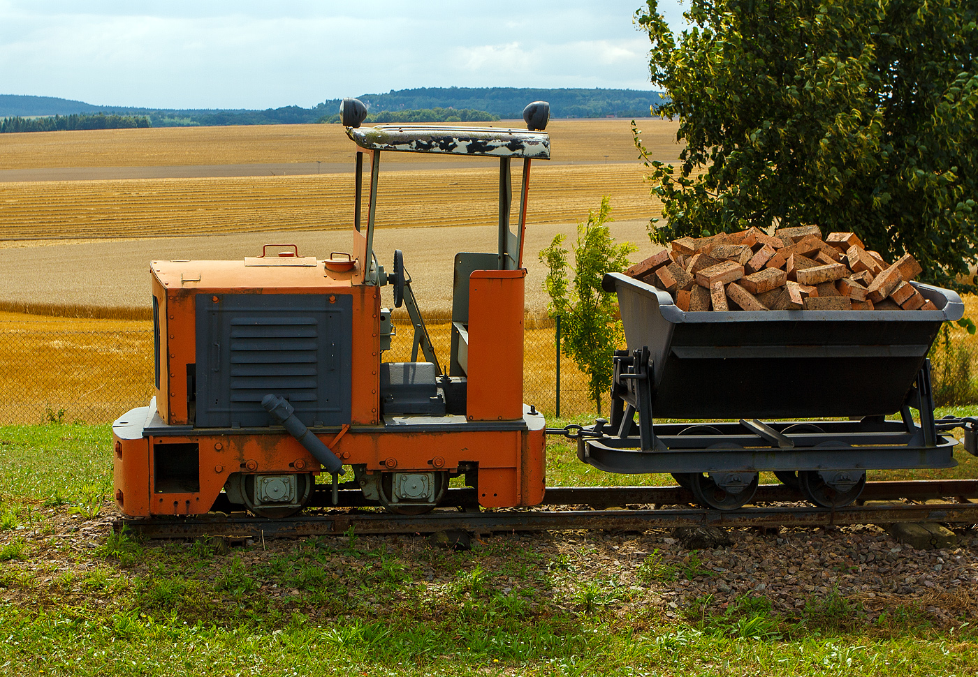 Die 600mm  LKM Ns1b  Diesel-Feldbahnlok, als Denkmallok mit zwei Loren bei Amand Umwelttechnik in Grumbach bei Freital, am 26.08.2013 aufgenommen vom Gehweg aus. 

Die Lok vom Typ Ns 1 b wurde 1960 vom VEB Lokomotivbau Karl Marx Babelsberg (LKM) unter der Fabriknummer 260103 gebaut und an den VEB Ziegelwerk in Grumbach geliefert. 

Diese kleinste Lok des LKM-Typenprogramms entspricht in Aufbau, Größe und Leistung der Jung-Lok EL 105, sogar das Getriebe beider Loks ist austauschbar. Mit ihrem geringen Gewicht und dem kurzen Achsstand war sie auch auf Gleisanlagen mit kleinem Schienenprofil und schwachem Unterbau zu fahren. Der ursprüngliche stehende Einzylindermotor wurde später (wie bei vielen Ns 1 b) durch einen Vierzylinder-V-Motor ersetzt, was Improvisationen an der Auspuffanlage erforderlich machte: An beiden Seiten der Motorverkleidung wurden die Bleche aufgeschnitten und Auspuffrohre mit Schalldämpfern durchgeführt.

Technische Daten:
Hersteller:  LKM
Fabriknummer:  247418
Baujahr:  1957
Spurweite: 600 mm (Lieferbar war 485 mm – 600 mm)
Bauart:  B-dm
Leistung:  15 PS Nenndrehzahl:  1500/min
Dienstgewicht:  2,8 t
Länge über Puffer:  2.320 mm
Breite:  1.020 mm
Höhe:  2.355 mm (mit Führerhaus)
Achsstand:  720 mm
Zugkraft:  500 kg
Geschwindigkeit:  8 km/h
Kleinster bef. Halbmesser:  7,5 m
Treibraddurchmesser:  376 mm
Leistungsübertragung:  mechanisch, Kette
Übersetzungsstufen:  2
Bremse:  Handhebelbremse
Kupplungstyp:  Ketten-Kupplung

Obwohl von der Type NS 1 ca. 700 Stück gebaut wurden, hat ihre Zahl nach der deutschen Einheit erheblich abgenommen. Während die Stillegung von Feldbahnen in der BRD seit den 60er Jahren allmählich verlief, vollzog sich dieser Prozess in den neuen Bundesländern durch Werksschließungen oder Umstellung der Förderung auf LKW oder Bandförderung innerhalb weniger Jahre. 
