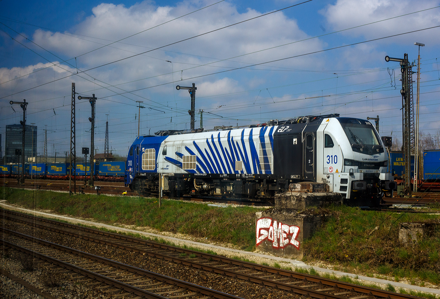 Die an die LOKOMOTION Gesellschaft für Schienentraktion mbH (München) vermietete Stadler EURO 9000 - 2019 311-0 (90 80 2019 311-0 D-ELP) der ELP - European Loc Pool AG (Frauenfeld/CH) steht am 02 April 2025 in München/Ost. Aufnahme aus einem Zug heraus.

Die sechsachsige Lok wurde 2023 von Stadler Rail Valencia S.A.U. in Albuixech (Spanien) unter der Fabriknummer 4072 gebaut und an die ELP - European Loc Pool AG in Frauenfeld (CH) ausgeliefert.

Die Stadler EURO 9000 ist eine Co'Co'- DualModeLok, unter Oberleitung hat sie eine gewaltige Leistung am Rad von 9.000 kW (12.236 PS), eine Anfahrzugkraft von 500 kN und eine Dauerzugkraft 430 kN. Im Dieselbetrieb beträgt die Leistung immerhin noch 1.900 kW (2.582 PS).
