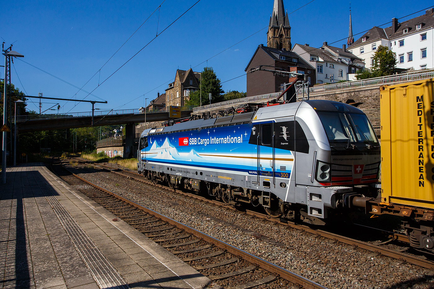 Die an die SBB Cargo International AG vermietete Siemens Vectron MS - 193 110  Zugersee  (91 80 6193 110-4 D-Rpool) der Railpool GmbH (München) fährt am 18 August 2025 mit einem Containerzug durch den Bahnhof Kirchen/Sieg in Richtung Siegen. 

Die SIEMENS Vectron MS (X4E) wurde 2023 von Siemens Mobility in München-Allach unter der Fabriknummer 23293 gebaut. Die mit 6.400 kW konzipierte Mehrsystemlok ist in der Variante A22 ausgeführt und hat so die und hat so die Zulassungen und entspr. Länderpakete für Deutschland, Österreich, Schweiz, Italien und die Niederlande (D / A / CH / I / NL), wobei z.Z. CH und I noch durchgestrichen sind. Sie ist die 300th Lokomotive der Railpool. 