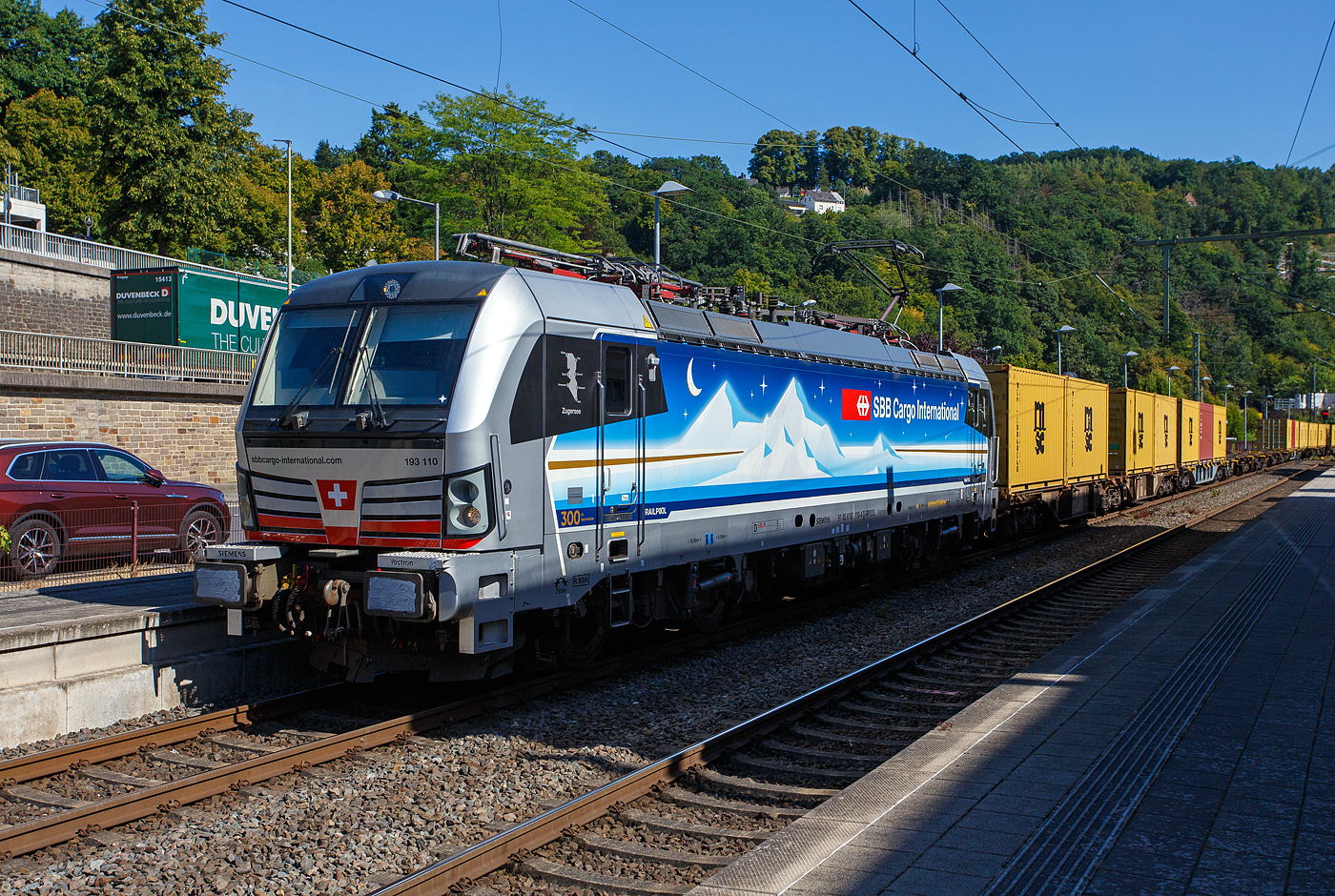 Die an die SBB Cargo International AG vermietete Siemens Vectron MS - 193 110  Zugersee  (91 80 6193 110-4 D-Rpool) der Railpool GmbH (München) fährt am 18 August 2025 mit einem Containerzug durch den Bahnhof Kirchen/Sieg in Richtung Siegen. 

Die SIEMENS Vectron MS (X4E) wurde 2023 von Siemens Mobility in München-Allach unter der Fabriknummer 23293 gebaut. Die mit 6.400 kW konzipierte Mehrsystemlok ist in der Variante A22 ausgeführt und hat so die und hat so die Zulassungen und entspr. Länderpakete für Deutschland, Österreich, Schweiz, Italien und die Niederlande (D / A / CH / I / NL), wobei z.Z. CH und I noch durchgestrichen sind. Sie ist die 300th Lokomotive der Railpool. 