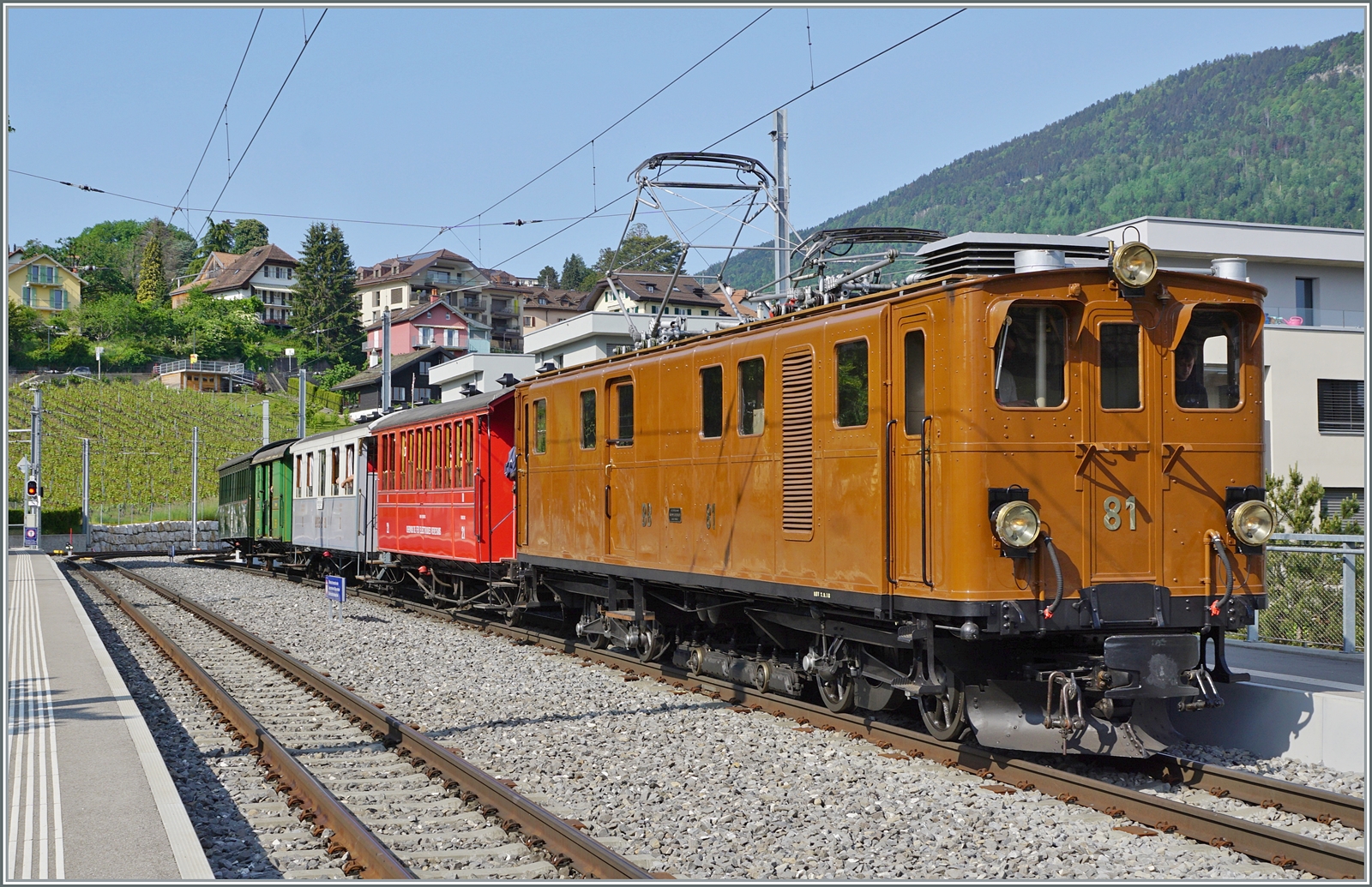 Die Bernina Bahn RhB Ge 4/4 81 der Blonay-Chamby Bahn ist mit ihrem recht gut besetzten Riviera Belle Epoque Zug von Chaulin auf dem Weg von Chaulin nach Vevey und wartet in St-Légier Gare auf den Gegenzug.

28. Mai 2023 