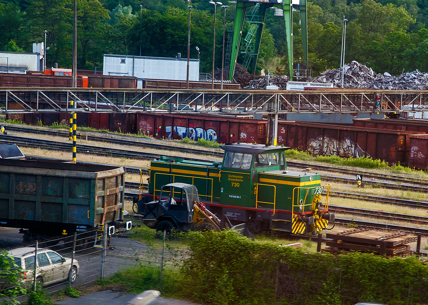 Die DE 730 der Dortmunder Eisenbahn GmbH (98 80 0262 002-5 D-DE), ex Krupp Stahl AG (Werk Bochum) KS-WB 631, eine MaK G 761 C, am 31.05.2022 bei Dortmund. Aufnahme aus dem Zug heraus.

Die dreiachsige Lok wurde 1978 von der Maschinenbau Kiel GmbH (MaK) unter der Fabriknummer 700023 gebaut und an die Krupp Stahl AG geliefert, 1994 bernahm die DE den Bahnbetrieb im KS Werk Bochum und die Lok ging an die Dortmunder Eisenbahn GmbH, wo sie nun als 730 gefhrt wird. Zum 01.01.2007 erhielt sie die NVR-Nummer 98 80 0262 002-5 D-DE.

Die Lokomotive MaK G 761 C ist eine dieselhydraulische Lokomotive, die von der Maschinenbau Kiel (MaK) gebaut wurde. Sie war zusammen mit der leistungsstrkeren G 762 C die erste Bauart des 3. Typenprogramms der MaK, das ab 1977 angeboten wurde. Gemeinsam war diesem Programm, dass nicht mehr auch im Schiffbau verwendete langsam laufenden Motoren aus eigener Produktion, sondern schnelllaufende Fremdmotoren eingebaut wurden, bei diesem Modell von MTU. Auch waren die Fhrerhuser aus Sicherheitsgrnden nicht mehr direkt vom Boden, sondern nur ber den Umlauf erreichbar. Die MaK G 761 C hat drei im Rahmen sitzende Achsen, die ber Gelenkwellen angetrieben werden. Sie ist mit zwei verschiedenen Motoren mit 470 kW bzw. sptere 500 kW angeboten worden. Sie erreicht eine maximale Geschwindigkeit von bis zu 55 km/h. Ihre Dienstgewicht betrgt bis zu 66 t, der Tankinhalt 1.500 l. 

Zwischen 1977 und 1982 wurden 18 Lokomotiven, davon fnf (wie diese hier) mit dem leistungsschwcheren Motor, gebaut. Die Lokomotiven wurden berwiegend an Werk- und Hafenbahnen, vor allem in die Montanindustrie, geliefert. Allein sieben Loks gingen an die Krupp Stahl AG. Je zwei Loks kauften die Shell AG und die Neusser Eisenbahn. Alle 18 gebauten Lokomotiven befinden sich noch im Einsatz. Im Deutschen Fahrzeugeinstellungsregister wurde fr diese Bauart die Baureihennummer 98 80 0262.0 vergeben.

TECHNISCHE DATEN:
Spurweite:  1.435 mm (Normalspur)
Achsfolge:  C
Lnge ber Puffer:  9.870 mm
Achsstand: 3.800 mm
grte Breite:  3.100 mm
grte Hhe ber Schienenoberkante:  4.220 mm
Treibraddurchmesser:  1.000 mm (neu)
kleinster befahrbarer Gleisbogen: 40 m
Dienstgewicht:  54 - 66 t
Kraftstoffvorrat:  1500 l
Motor:  Sechszylinder-MTU-Dieselmotor, Typ  MTU 6V 331 TC11 (sptere Vers.TC12)
Leistung: 470 kW  (sptere Vers. 500 kW)
Nenndrehzahl: 1.050 U/min
Getriebe: Voith L4r4zU2
Leistungsbertragung: hydraulisch
Hchstgeschwindigkeit:  30 - 55 km/h
