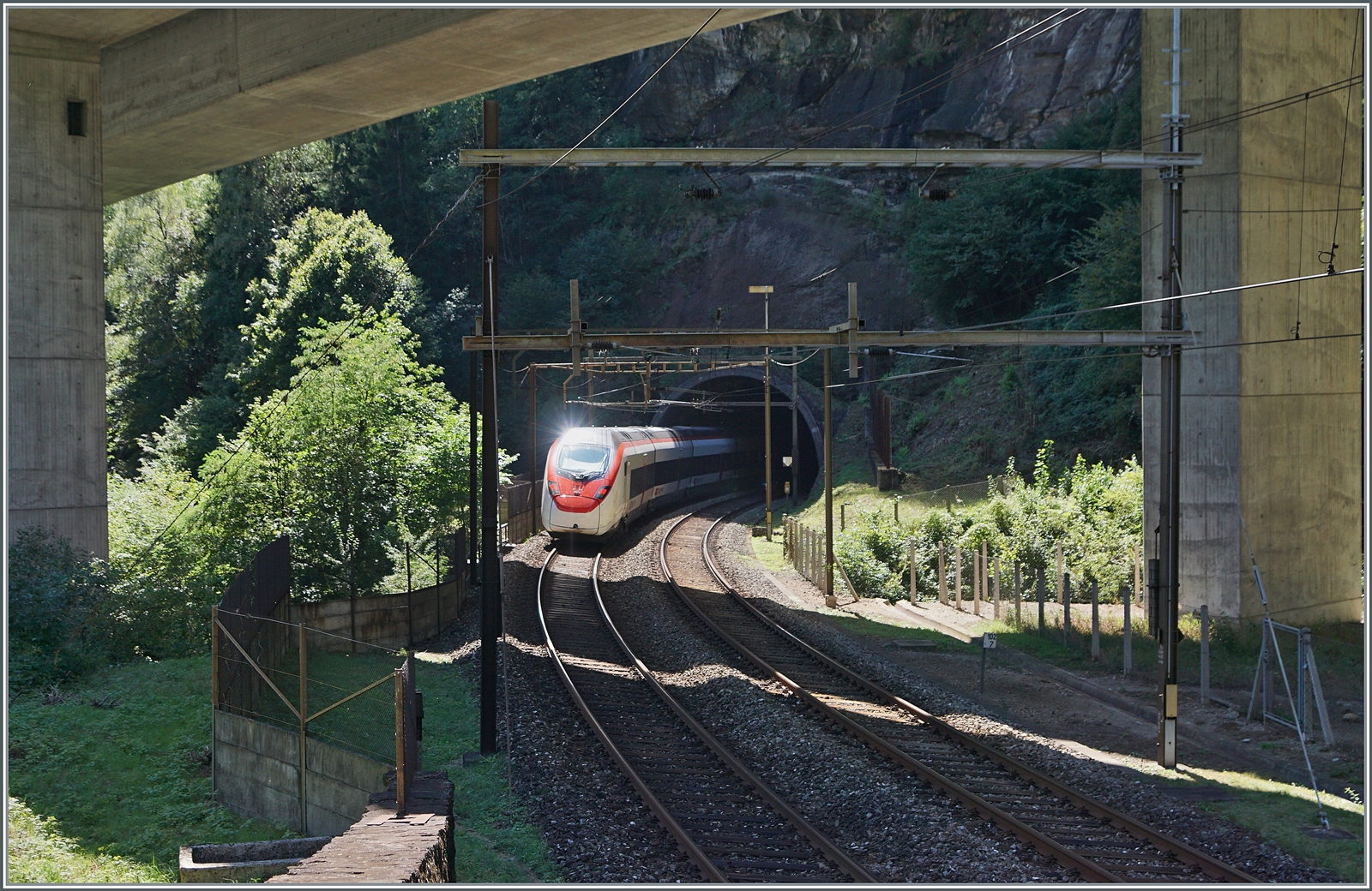 Die Gotthard Panorama Strecke bietet nicht nur herrliche Panorma-Bilder sondern an wenigen Stellen eher Tristesse: In der vom Beton der Autobahn A 2 verschandelten Landschaft fährt ein (umgeleiteter) SBB RABE 501  Giruno  auf dem Weg in Richtung Lugano in den Polmengokehrtunnel. 

4. September 2023