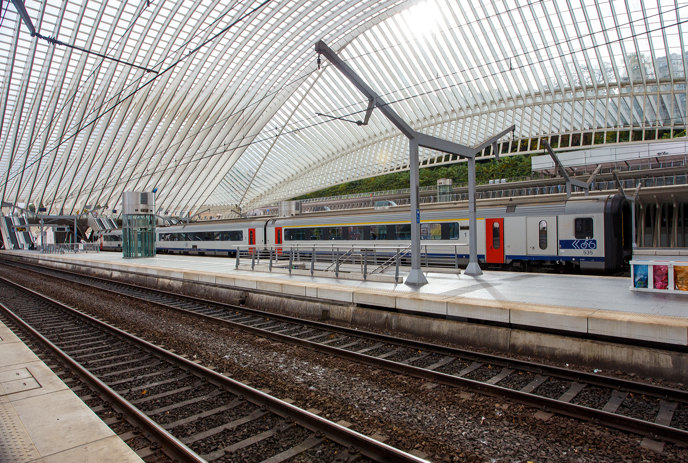 Die Gumminase SNCB/NMBS Triebzug AM 96 - 535 (AM = Automotrice), ein 3 kV Einsystemtriebzug mit GTO-Traktionsstromrichter am 21 Oktober 2025 im Bahnhof Liège Guillemins (Lüttich-Guillemins). Er fährt als S-Zug Lüttich (Train S Liège) der Linie S 42, die Verbindung (Liers – Herstal – Liège-Saint-Lambert – Liège-Guillemins –Seraing – Flémalle-Haute).

Die Reihe AM 96 der Belgischen Staatsbahn ist eine Reihe von 160 km/h schnellen dreiteiligen Elektrotriebfahrzeug-Einheiten. Jede Einheit besteht aus je einem Wagen der Typen Bx, B und ADx. Die Züge werden hauptsächlich im innerbelgischen Schnellzugdienst (IC und IR) der NMBS/SNCB eingesetzt, erreichen aber auch auf drei grenzüberschreitenden InterCity-Linien Lille (Frankreich) und Luxemburg (Stadt). Charakteristisch ist bei diesen Fahrzeugen der Führerstand, welcher von einer Gummiwulst umgeben ist - weshalb diese Fahrzeuge liebevoll Gumminasen oder auch abwertend Klobrillen genannt werden - und dessen Mittelteil (Steuertisch), welches bei der Vereinigung von mehreren Einheiten seitlich wegklappbar ist. Aufgrund ihrer äußeren und technischen Ähnlichkeit mit der dänischen Baureihe MF werden sie auch Deense neus („Dänische Nase“) genannt.

Fahrzeugnummern:
441-490: Zweisystemfahrzeuge für 3 kV= und 25 kV~
501-547: Einsystemfahrzeuge 3 kV = mit GTO-Traktionsstromrichter
548-570: Einsystemfahrzeuge 3 kV = mit IGBT-Traktionsstromrichter

TECHNISCHE DATEN der AM 96:
Hersteller: BN (La Brugeoise et Nivelles) / ACEC (Ateliers de contruction électriques de Charleroi)
Anzahl: 120
Baujahr(e): 1996–1999
Achsformel: Bo'Bo'+2'2'+2'2'
Spurweite: 1.435 mm (Normalspur)
Länge über Kupplung: 79.200 mm
Drehzapfenabstand: 18.400mm B Wagen; 18.700mm Bx und ADx Wagen
Achsabstand im Drehgestell: 2.560 mm
Triebraddurchmesser: 1.010 mm (neu)
Laufraddurchmesser: 920 mm (neu)
Breite: 2.860 mm
Höchstgeschwindigkeit: 160 km/h
Stundenleistung: 1.400 kW
Stromübertragung: Oberleitung
Anzahl der Fahrmotoren: 4 Asynchron-Drehstrommotore vom Typ 4EXA3046
Max. Drehmoment eines Motors: 1.683Nm
Übersetzungsverhältnis auf die Achsen: 1: 4,565
Hersteller Laufdrehgestelle: ANF
Hersteller Triebdrehgestelle: ACR
