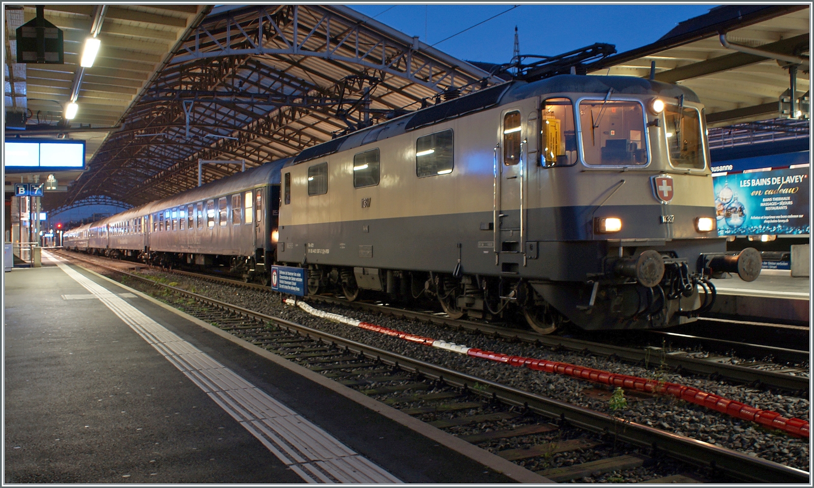 Die IRSI/IGE Re 4/4 II 11387 (Re 421 387-2) wartet mit ihrem ZRT Silvesterzug im Stile der Belle Epoque in Lausanne auf die Abfahrt nach Frankfurt am Main HBF. Es ist schon einige Zeit her, dass ich in Lausanne eine Re 4/4 II vor einem Reisezug fotografieren konnte. Die 1984 gebaute Re 4/4 II 11387 in der Rheingold-Farbgebung gefällt mir aber besonders gut. 

30. Dezember 2023