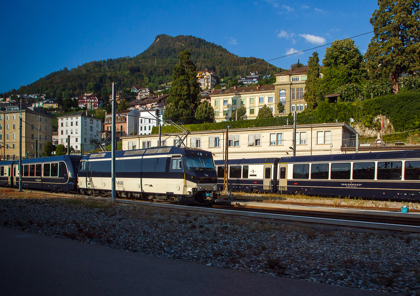 Die MOB Ge 4/4 8004 ist am 07.09.2023 mit einem GPX - GoldenPass Express (Stadler GPX-Wagen mit variablem Drehgestellen) beim Bahnhof Montreux abgestellt. Bild aus einem Zug heraus.