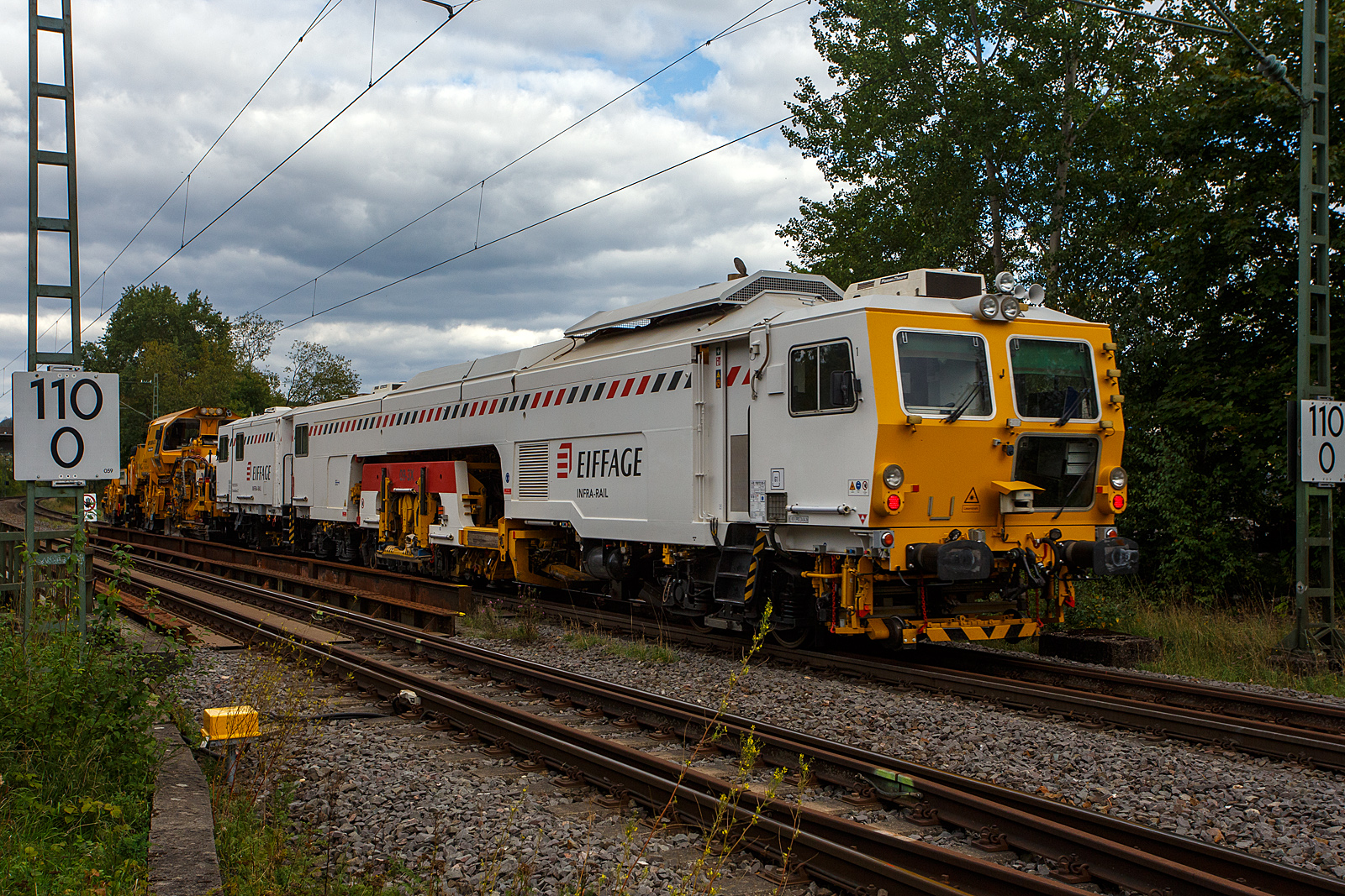 Die Plasser & Theurer Schotterverteil- und Planiermaschine USP 2000-C2-2, VdM-Nummer D-ERD 99 80 9125 010-5, gekuppelt mit der Plasser & Theurer Gleisstopfmaschine 09-3X, VdM-Nummer D-ERD 99 80 9121 001-8, beide Maschinen geh�ren der Eiffage Rail (NL der Eiffage Infra-Bau GmbH, Herne), fahren am 10 September 2026 durch Eiserfeld in Richtung Siegen. Zurzeit wird an der Ruhr-Sieg-Strecke u.a. zwischen Siegen und Kreuztal gebaut. 

VdM-Nummer steht f�r: Verzeichnis der gleisfahrbaren Baumaschinen und Zweiwegefahrzeuge, fr�her hie� es Schweres Nebenfahrzeug Nr..

Die USP 2000-C2-2 wurde 2017 von Plasser & Theurer in Deutschland unter der Fabriknummer 6503 gebaut. Die Gleisstopfmaschine 09-3X wurde 2010 von Plasser & Theurer in Linz/Donau (�sterreich) gebaut.