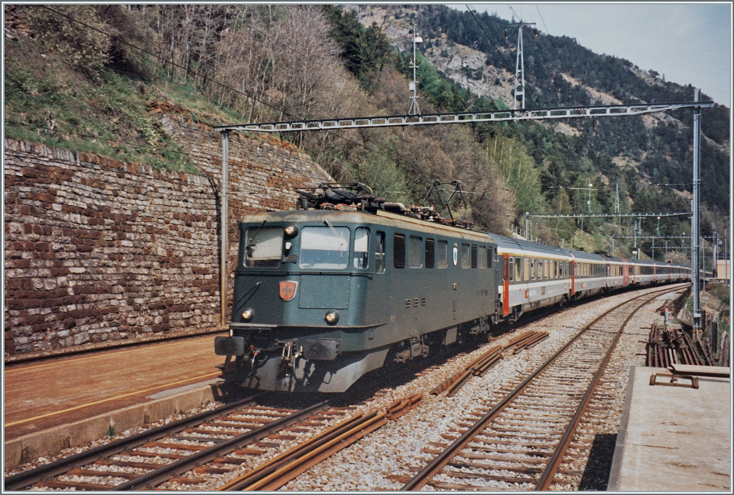 Die SBB Ae 6/6 11468  Lenzburg  ist im Frühsommer mit dem EC  Matterhorn  von Brig nach Wiesbaden auf der BLS Südrampe bei Hohtenn unterwegs.

Analogbild vom Mai 1995