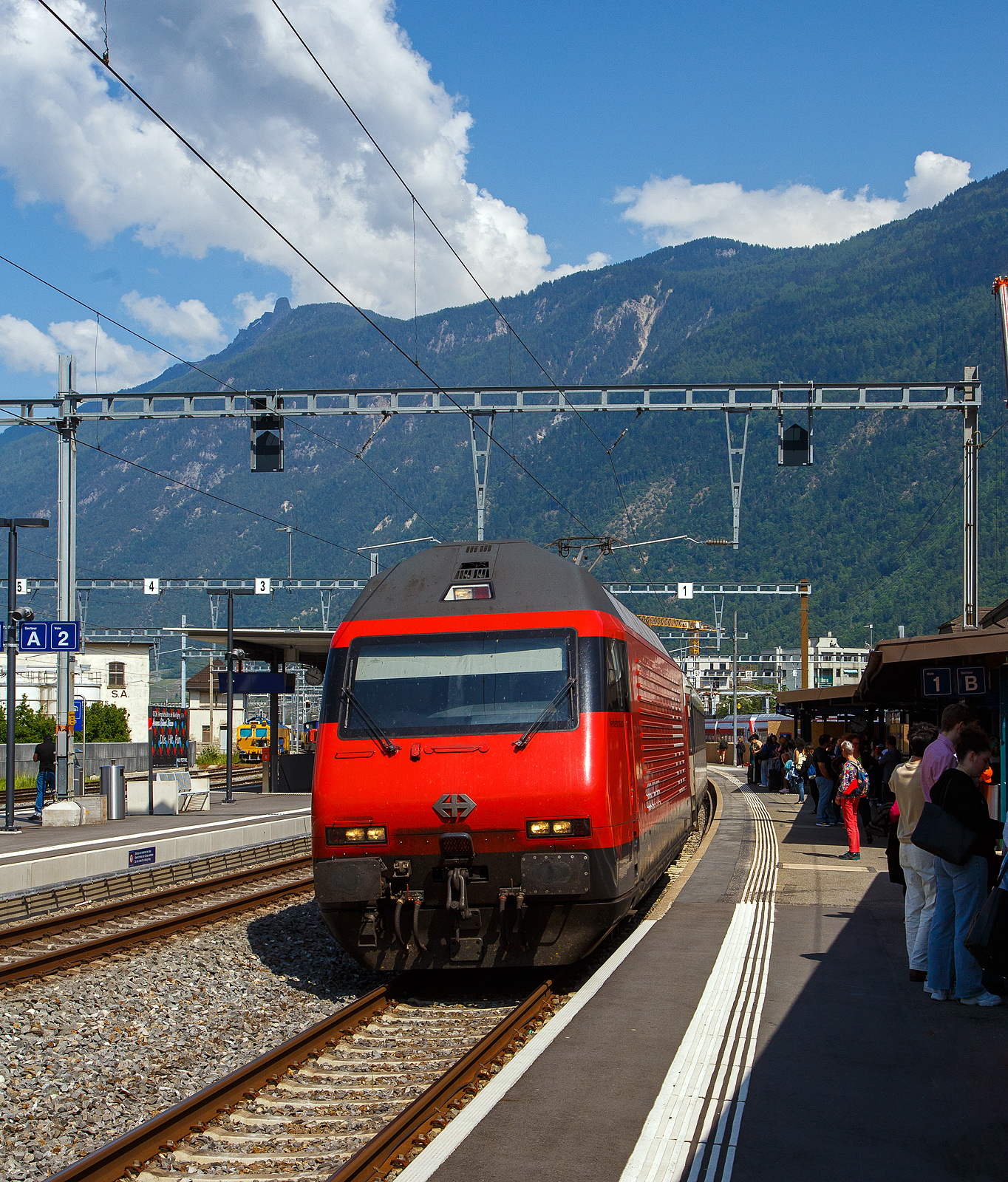 Die SBB Re 460 069-8  Verkehrshaus  (91 85 4 460 069-8 CH-SBB) fährt am 26 Mai 2023, mit dem IR 90 von Brig nach Genève-Aéroport (Umlauf IR 1724), in den Bahnhof Martigny ein. Da der Zug recht lang war wurde im Sandwich gefahren, so war am Zugschluss die SBB Re 460 041-7  Mendrisiotto .

Die Re 460 069-8 wurde 1993 von der SLM (Schweizerischen Lokomotiv- und Maschinenfabrik in Winterthur) unter der Fabriknummer 5542 gebaut, der elektrische Teil ist von der ABB (Asea Brown Boveri).

