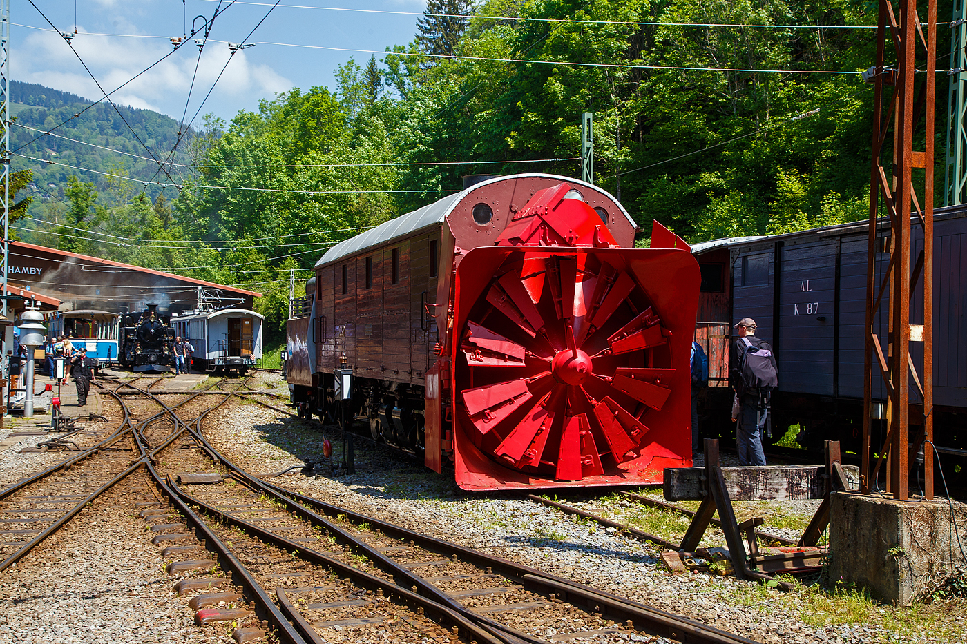 Die Selbstfahrende Dampfschneeschleuder R 1052 (ex Berninabahn) BB R 1052, ex RhB R 14, ex RhB Xrot d 9214), der Museumsbahn Blonay-Chamby, hier am 27.05.2023 auf dem Museums-Areal der (BC) in Chaulin.

Die Schneeschleuder wurde 1912 von der Schweizerischen Lokomotiv- und Maschinenfabrik (SLM) unter der Fabriknummer 2299 als R 1052 für die Berninabahn gebaut, 1944 um bezeichnet in RhB R 14, 1954 um nummeriert in RhB Xrot d 9214 (Die Bezeichnung Xrot d setzt sich zusammen aus: X = Dienstfahrzeug, rot = rotierend, d = dampfgetrieben.), 1990 ging sie an die DFB, 1996 wurde sie im Tausch gegen die ehemalige RhB R 12 von der B-C übernommen.

Dieses Fahrzeug wie auch das heute noch bei der RhB betriebsfähige Schwesterfahrzeug Xrot d 9213 (ex BB R 1051) sind dampfgetriebene Schneeschleudern mit eigenem Antrieb die für die Berninabahn (BB) gebaut wurden, die seit 1944 zur Rhätischen Bahn gehört. Im Gegensatz zu den bisher gebauten Fahrzeugen, auch der zwei Dampfschleudern der RhB-Stammstrecke, handelt es sich bei den beiden Bernina-Schleudern um selbstfahrende Fahrzeuge. Die Berninabahn entschied sich hierzu, weil in den engen Kurven mit nicht genügend hoher Kraft geschoben werden konnte und die Bahn selbst keine Fahrdraht-unabhängigen Triebfahrzeuge besaß. Die Schleudern wurden dennoch normalerweise mit Schiebetriebfahrzeugen eingesetzt, damit die gesamte Kesselleistung für die Dampfmaschine des Schleuderrades zur Verfügung stand.

Mit der Übernahme der Berninabahn durch die Rhätische Bahn (RhB) erhielten die beiden Schleudern die neuen Bezeichnungen R 13 und R 14, 1950 dann Xrot d 9213 und 9214. Die beiden Fahrzeuge befanden sich bis 1967 im regelmäßigen Einsatz und wurden danach durch modernere Schleudern ersetzt. Die Xrot d 9213 wird von der RhB im Heimatdepot in Pontresina weiterhin betriebsfähig gehalten. Sie wird heute vor allem zu touristischen Zwecken noch betrieben, und zwar im Rahmen so genannter Fotofahrten; zuweilen kommt sie aber auch noch bei der Räumung zum Einsatz.

Die Achsformel ist C'C', das Fahrzeug verfügen nach Bauart Meyer über zwei dreiachsige Triebdrehgestelle die durch vier Zylinder angetrieben werden, diese befinden sich unten mittig zwischen den Triebgestellen, darüber befindet sich der Antrieb für die Schneeschleuder, die von zwei weiteren Zylindern angetrieben wird. Der Durchmesser des Schleuderrads beträgt 2,5m, welches mit bis zu 170 U/min dreht und so bis zu drei Meter hohe Schneemassen beseitigen kann.
Gekuppelt ist die Schneeschleuder mit einem zweiachsigen Tender.

Die Xrot d 9214 wurde am 26. Januar 1968 zu einem einmaligen Großeinsatz auf der Arosabahn herangezogen. Geschoben von zwei ABDe 4/4 hatte sie die tiefverschneite Strecke zwischen Langwies und Arosa zu räumen und benötigte für den nur acht Kilometer langen Abschnitt acht Stunden.

TECHNISCHE DATEN:
Gebaute Anzahl: 2 (BB 1051, BB 1052)
Hersteller: SLM
Baujahre: 1910 und 1912
Ausmusterung: 1967 (1052/ 9214), Die 1051 ist als RhB Xrot d 9213 betriebsfähig
Spurweite: 1.000 mm (Meterspur)
Achsformel: C'C'
Länge: 13.865 mm
Höhe: 3.800 mm
Breite: 2.800 mm, max. 3.600 mm
Gesamtradstand: 10.655 mm (inkl. Tender)
Kleinster befahrbarer Gleisbogen: R=45 m
Dienstgewicht: 45 t
Dienstgewicht mit Tender: 63,5 t
Höchstgeschwindigkeit: 35 km/h
Indizierte Leistung Antrieb: 221 kW
Indizierte Leistung Schneeschleuder: 368 kW
Treibraddurchmesser: 750 mm
Zylinderanzahl: 4 für Antrieb und 2 für Schneeschleuder
Kesselüberdruck: 14 bar
Wasservorrat: 7 m³
Kohlevorrat: 4 t