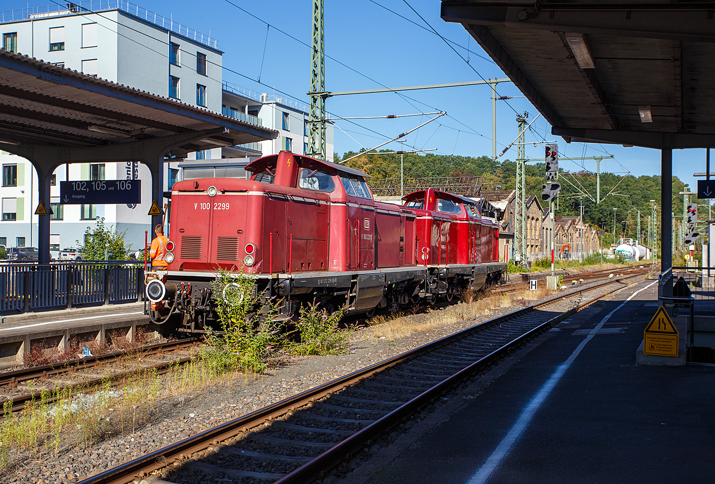 Eigentlich musste ich aufs ein anderes Gleis (106) um den RE 9 zu erreichen, aber bevor es in die Unterf�hrung ging konnte ich die beiden V 100.20 im Tandem noch ablichten. Die V 100 2299 alias 212 229-2 (92 80 1212 229.9 D-VEB) gekuppelt mit der V 100 2091 alias 212 209-1 (92 80 1212 209-1 D-VEB) beide der VEB - Vulkan-Eifel-Bahn Betriebsgesellschaft mbH, rangieren als Lokzug (Lz) am 12 August 2026 im Bahnhof Betzdorf/Sieg zur Dieseltankstelle. 

Die V 100 2091 wurde 1964 von MaK (Maschinenbau Kiel GmbH) in Kiel unter der Fabriknummer 1000227 gebaut und als V100 2091 an die DB ausgeliefert. Zum 01.01.1968 erfolgte die Umzeichnung in DB 212 091-3 und als diese fuhr sie bis zur Ausmusterung 2002 bei der DB Cargo AG. Im Jahr 2003 ging sie dann an die VEB, zum 01.01.2007 erhielt sie die NVR-Nummer 92 80 1212 209-1 D-VEB.

Die V 100 2299 wurde 1965 von MaK (Maschinenbau Kiel GmbH) in Kiel unter der Fabriknummer 1000346 gebaut und als V100 229 9 an die DB ausgeliefert. Zum 01.01.1968 erfolgte die Umzeichnung in DB 212 229-2 und als diese fuhr sie bis zur Ausmusterung 2002 bei der DB Cargo AG. Im Jahr 2002 ging sie dann an die VEB, zum 01.01.2007 erhielt sie die NVR-Nummer 92 80 1212 229-9 D-VEB.