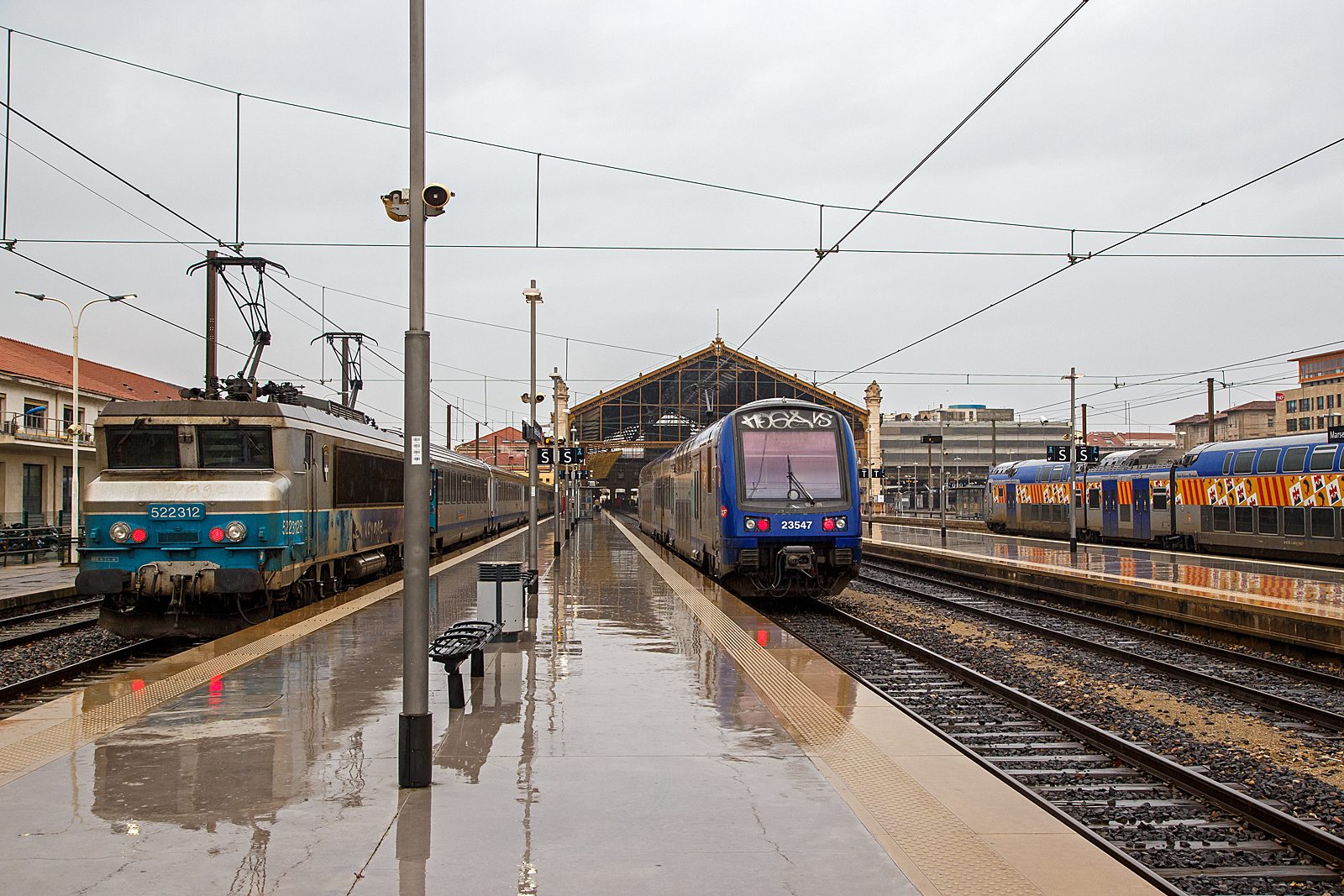 Ein Doppelstock-Triebzug der Baureihe Z 23500 (TER 2N PG) f�hrt am 25.03.2015, bei Regen, (Steuerwagen voraus 231547 / 23547) in den Bahnhof Marseille Saint-Charles ein. Links steht die SNCF BB 22312  Antibes / Juan-les-Pins  (BB 522312R bzw. UIC: F-SNCF 91 87 0022 312-) mit einem TER Regionalzug bereit.

Die zweiteiligen Doppelstockfahrzeuge Z 23500 entstanden als Ergebnis einer engen Zusammenarbeit zwischen der SNCF und den drei Regionen Nord-Pas-de-Calais, Rh�ne-Alpes und Provence-Alpes-C�te d'Azur in den fr�hen 1990er Jahren. Auf Basis des �Z 2N� (Z 20500) entstand so entsprechend den Bed�rfnissen der Regionen ein Doppelstocktriebzug der Baureihe Z 23500, bestehend aus Triebwagen und Steuerwagen f�r den komfortablen Regionalverkehr.  lm Herbst 1997 erschienen zun�chst die drei Prototypen Z 23501, 23502 und 23503 f�r ausf�hrliche Testfahrten in den Besteller Regionen, um etwaige Probleme und Unstimmigkeiten auszumerzen. Bis zum Jahr 2000 wurden insgesamt 80 Einheiten von Alstom und AMF (Ateliers du Nord de la France, heute Bombardier) gebaut.