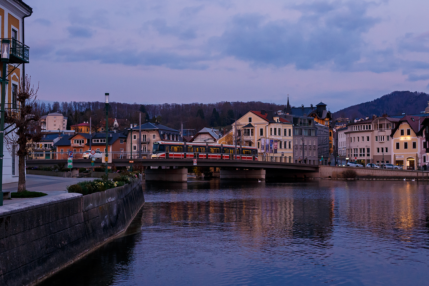 Ein fünfteiliger Meterspur-Straßenbahn-Triebwagen, ein STADLER Zweirichtungs-Multigelenk-Stadtbahnwagen in Niederflur-Bauweise vom Typ Tramlink V3 der neuesten Generation (Tramlink 2.0), der Stern & Hafferl Verkehrsgesellschaft m.b.H., fährt am Abend des 02 April 2025 in Gmunden, als Linie 161 „Traunseebahn“ nach Vorchdorf, über die Traunbrücke.