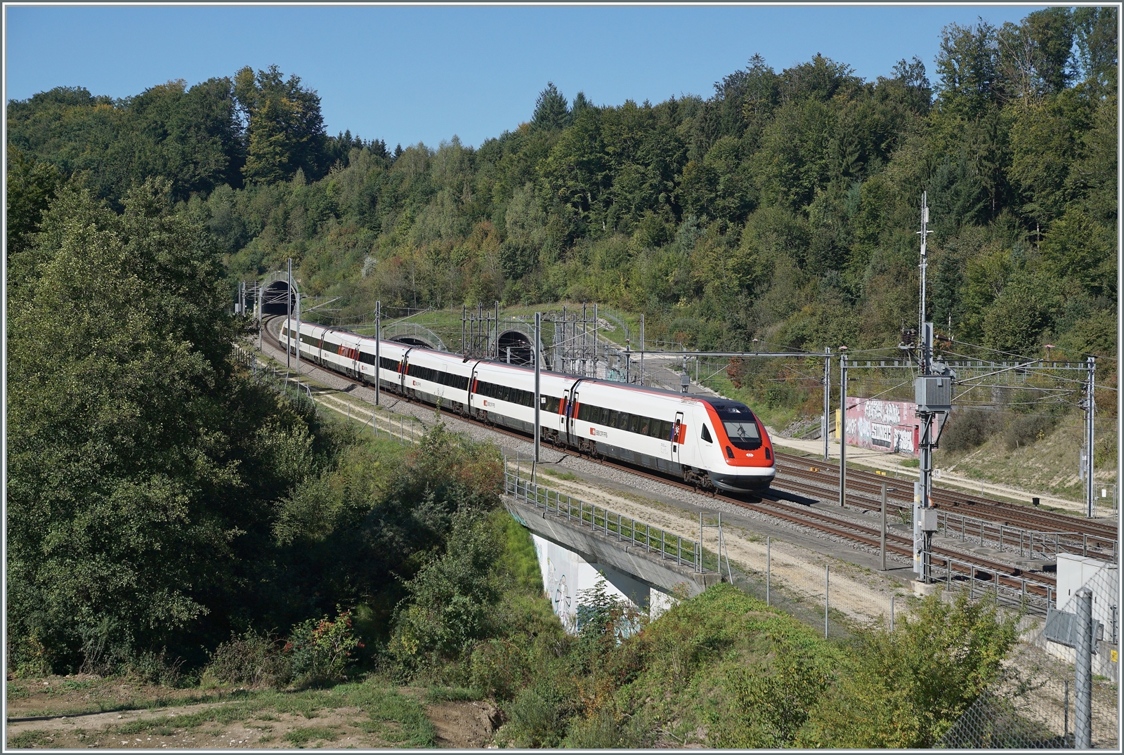 Ein ICN von Romanshorn nach Genève-Aéroport verlässt bei Wanzwil die NBS (Olten) Rothrist - Mattstetten (Bern) und fährt unmittelbar drauf in den 436 Meter langen Wolfacker Süd Tunnel ein. Es ist erstaunlich dass die kaum nennenswerte Erhebung  Oenzberg  fast wie auf einer Modellbahn einem Emmentaler Käse gleich mit drei Tunnel durchlöchert wurde: Links der bereits erwähnte Tunnel Wolfacker Süd, in der Mitte der Doppelspur Oenzberg-Tunnel mit 3173 Meter Länge und Rechts der Tunnel Wolfacker Nord mit 597 Meter Länge. Vielleicht noch erwähnenswert, dass unter dem Schlusswagen die Oenz fließt, welcher welche gut 200 Meter weiter der dort verlaufenen Strecken Herzogenbuchsee - Solothurn (1857 - 2004) eine heute noch bestehendes Viadukt bescherte,. 12. September 2022