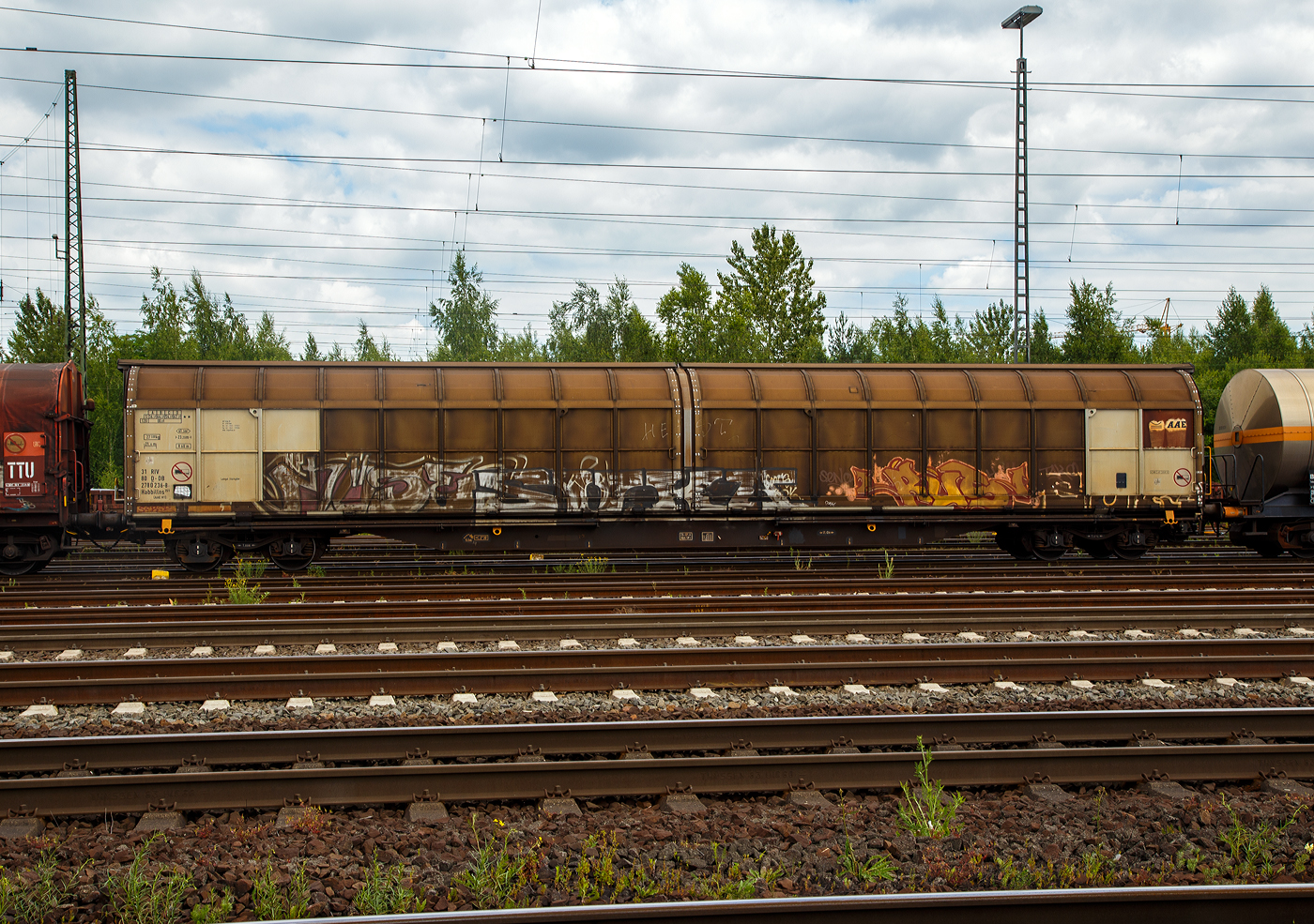 Ein recht langer vierachsiger großräumiger Drehgestell-Schiebewandwagen, 31 80 2780 236-8 D-DB, der Gattung Habbillns 351 (AAE H1), ex 31 68 2780 236-4, ein von der DB Cargo AG angemieteter Wagen der ehem. AAE Cargo AG (Baar/Schweiz), heute Teil der VTG, ist am 18.06.2017 im Gbf Koblenz-Lützel angestellt. 

Güterwagen mit vier Radsätzen (in 2 Drehgestellen), zweiteiligen Aluminium-Schiebewänden und sechs verriegelbaren Trennwänden. Diese großräumigen Wagen sind mit Schiebewänden ausgerüstet, die von einer Person bewegt werden können. Im geöffneten Zustand ist der Zugang zur halben Ladefläche von beiden Seiten möglich.

Be- und Entladen mit Gabelstaplern ist damit sowohl von einer Rampe als auch von ebener Erde möglich. Die Wagen sind für eine schonende Beförderung hochempfindlicher Güter verschiedener Art mit der Transportschutzeinrichtung  Verriegelbare Trennwände  ausgestattet, durch die der Wagenraum in einzelne Kammern unterteilt wird. Die verriegelbaren Trennwände rasten alle 45 mm in Lochleisten im Fußboden und am Obergurt des Wagens ein.

Der Wagen besitzt ein oben geführtes und unten auf Rollen laufendes Schiebewandsystem. Das Schiebewandsystem gestattet ein zum Wagenkasten paralleles Führen der Wand beim gesamten Öffnungs- und Schließvorgang. Die Betätigungsgestänge für das Schiebewandsystem befinden sich an den Stirnwänden.

Das Untergestell ist als Schweißkonstruktion hergestellt und besteht aus zwei durchlaufenden Außenlangträgern und Querträgern, die die Langträger verbinden. Der Fußboden besteht aus 30 mm dicken Sperrholzplatten, deren Oberseite mit einem rutschhemmenden Material beschichtet ist.

Zur Ladegutsicherung sind die Wagen mit vier verriegelbaren Trennwänden ausgerüstet.

Die Bedeutung der Gattungs- und Kennbuchstaben (hier Habbillns):
H = Gedeckter Wagen in Sonderbauart
a = mit 4 Achsen
bb = Nutzbare Länge über 22 m
i = Schiebewände
ll = mit verriegelbaren beweglichen Trennwänden
n = Lastgrenze über 60 Tonnen
s = für eine Höchstgeschwindigkeit von 100 km/h (beladen) geeignet

TECHNISCHE DATEN:
Hersteller: Waggonbau Niesky (ca. 1995)
Spurweite: 1.435 mm (Normalspur)
Anzahl der Achsen: 4 (in zwei Drehgestellen)
Länge über Puffer: 23.200 mm
Drehzapfenabstand: 17.720 mm
Achsabstand im Drehgestell: 1.800 mm
Laufraddurchmesser: 920 mm (neu)
Ladelänge: 21.600 mm (mit Trennwänden) / ca. 22.150 mm (ohne Trennwände)
Ladebreite: 2.840 mm
Ladefläche: 61,3 m²
Laderaum: ca. 163 m³
Fußbodenhöhe von SOK: 1.200 mm
Min. befahrbarer Kurvenradius: R 60 m
Eigengewicht: 27.500 kg
Max. Ladegewicht: 62,5 t (ab Streckenklasse D)
Maximale Radsatzlast: 22,5 t
Schiebewandöffnung:  2 x ca. 10.800 mm x 2.800 mm
Höchstgeschwindigkeit: 100 km/h (beladen) / 120 Km/h (leer)
Bauart der Bremse: Ch-GP-A (max. 59 t)
Verwendungsfähigkeit: RIV

Die AAE Ahaus Alstätter Eisenbahn AG mit Sitz in Baar (Schweiz) war mit 30.000 Güterwagen einer der größten privatwirtschaftlichen Güterwagenvermieter in Europa. Sie gehört seit Anfang 2015 zur VTG AG. Zunächst wurden die Waggons mit einer neuen Logo-Kombination aus dem der VTG und den AAE-Schriftzeichen versehen. 2018 war die Eingliederung in die VTG weitgehend vollzogen, die Vermietung der Waggons erfolgt über die VTG. Waggons tragen aber noch das Halterkürzel AAEC. Niederlassungen bestanden in allen größeren europäischen Ländern. Instandsetzungen und Hauptuntersuchungen der Güterwagen wurden europaweit durchgeführt.
