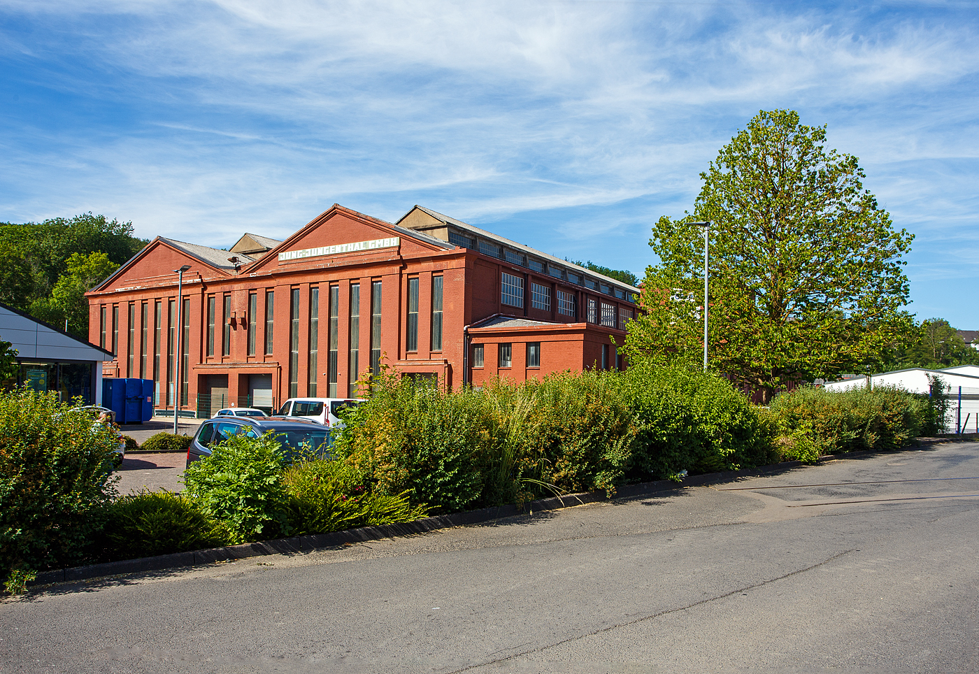 Ein Teil der Hallen der ehemalige Lokomotivfabrik Arnold Jung Jungenthal, in Kirchen/Sieg hier am 28 Mai 2026. Rechts in der Stra�e liegt noch ein letztes St�ckchen der  Asdorftalbahn  - Bahnstrecke Kirchen - Freudenberg (ex KBS 361 / Streckennummer 2882).... 

Die letzte Lok (Fabriknummer 12 143) wurde 1987 gebaut, eine Pressluftgubenlok Pz 45. Insgesamt wurden mehr als 12.000 Lokomotiven gefertigt, unter anderem 1959 mit der 23 105 die letzte �berhaupt an die DB gelieferte Neubaudampflok.

Gegr�ndet wurde die Firma als Jung & Staimer OHG am 13. Februar 1885 von Arnold Jung und Christian Staimer. Am 3. September 1885 wurde die erste Lokomotive ausgeliefert. 1913 erfolgte die Umbenennung in Arnold Jung Lokomotivfabrik GmbH, Jungenthal. 1976 wurde die Lokomotivproduktion zugunsten anderer Produkte wie Werkzeugmaschinen, Transportwagen, Panzerplatten, Kr�ne und Br�ckenausleger aufgegeben.

Die Produktion wurde am 30. September 1993 eingestellt, das Werk geschlossen. Die Jung-Jungenthal GmbH besteht jedoch weiterhin als „Jungenthal Wehrtechnik GmbH“, diese geh�rt seit 2007 zum Flensburger Fahrzeugbau. Auf dem Freigel�nde neben der Lokfabrik steht heute ein Lebensmitteldiscounter.